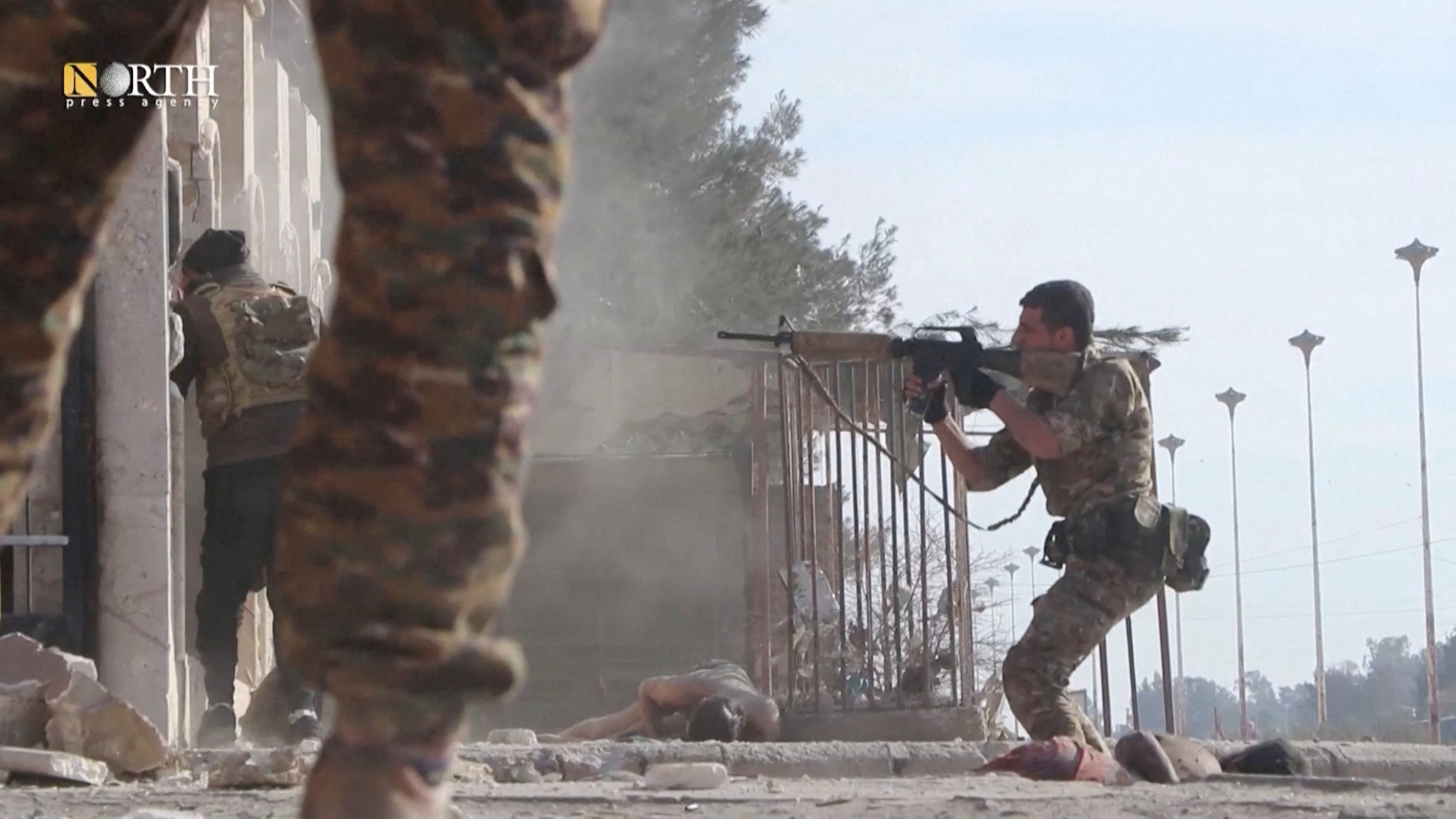 A Syrian Democratic Forces soldier points a gun outside a prison while in clash with the ISIL fighters in Hasakeh