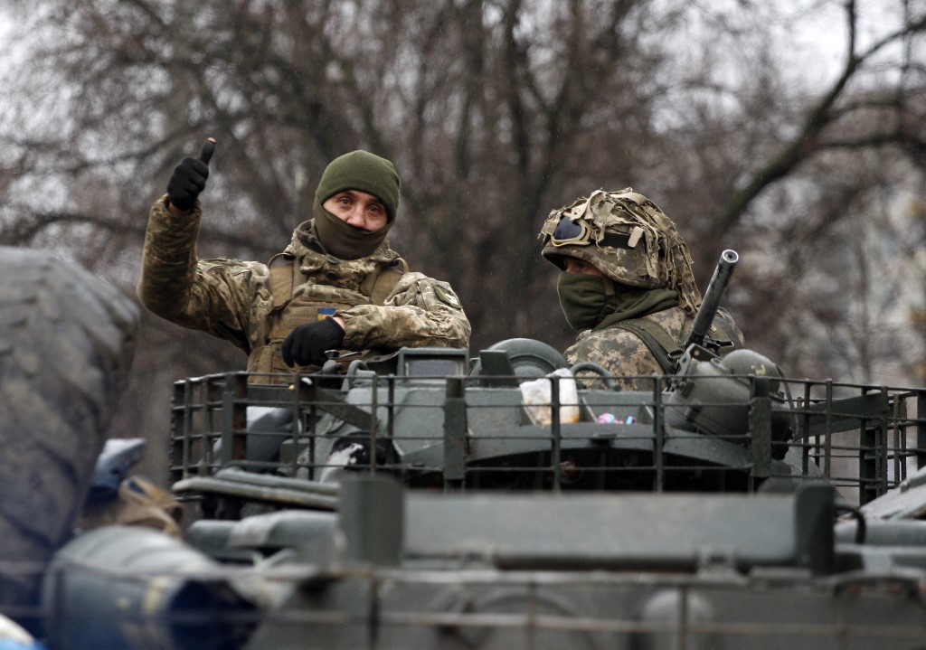 A Ukrainian serviceman gives a thumbs-up sign riding atop a military vehicle