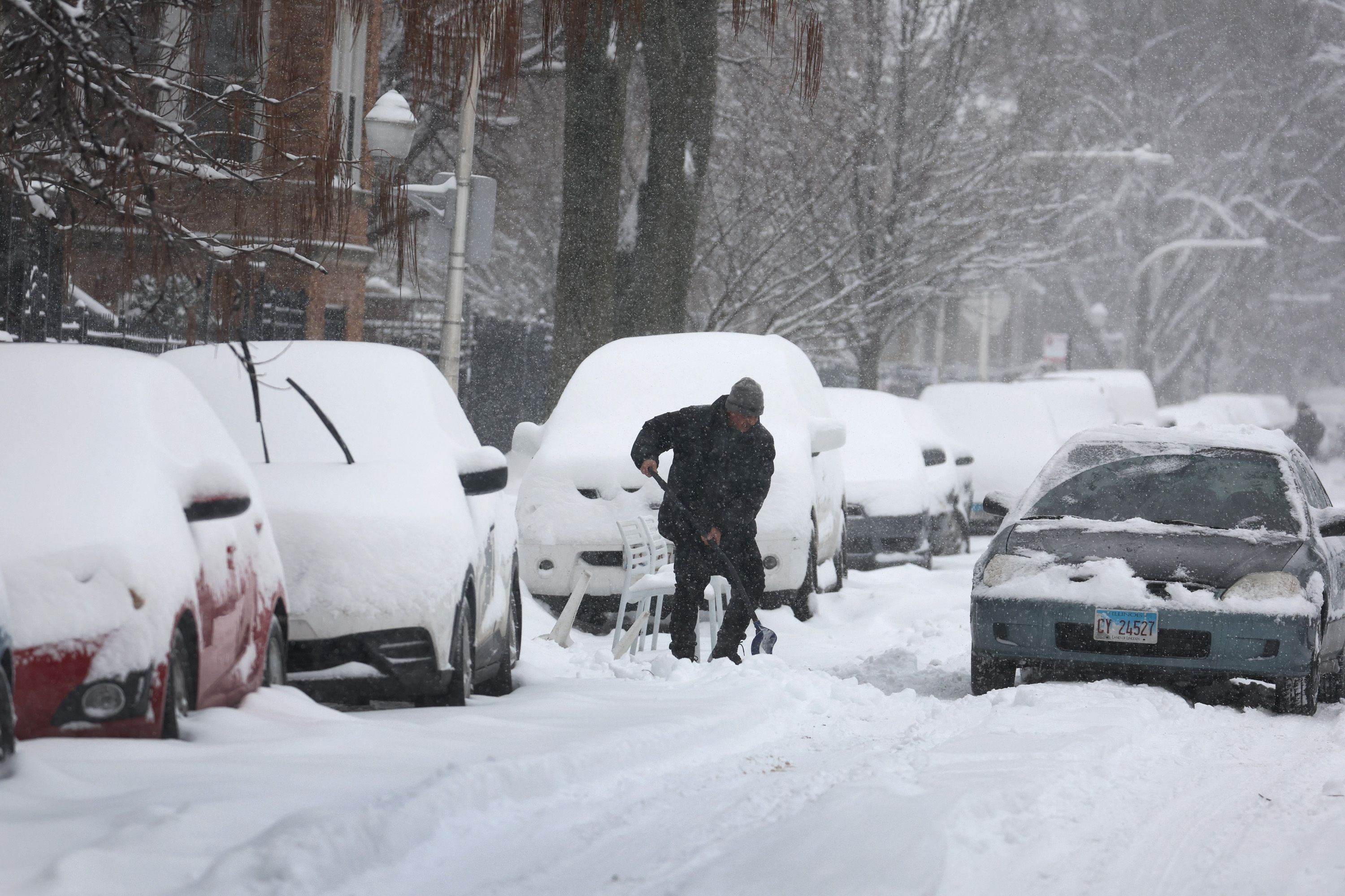 A resident shovels a parking space
