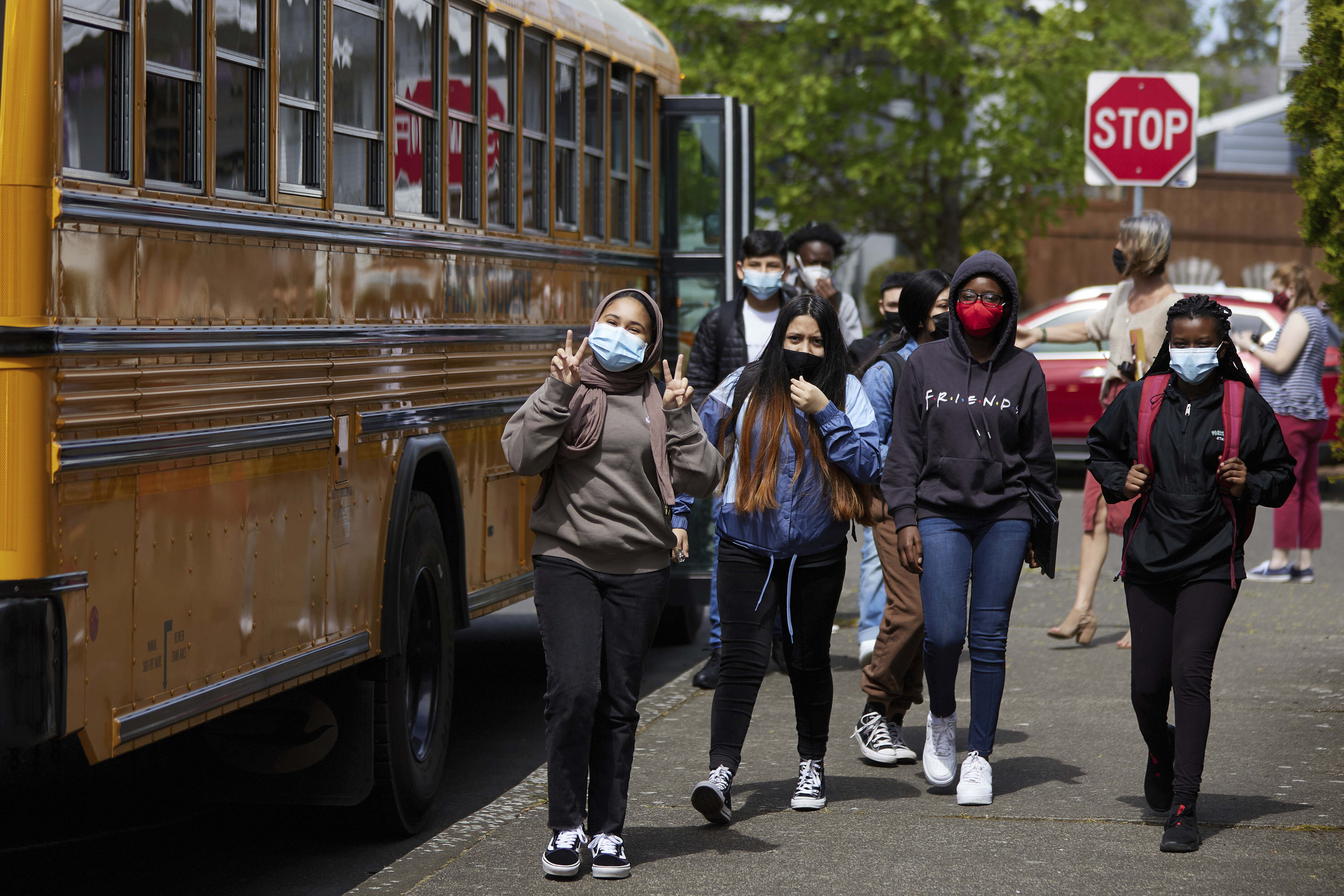 Children wearing masks beside school bus