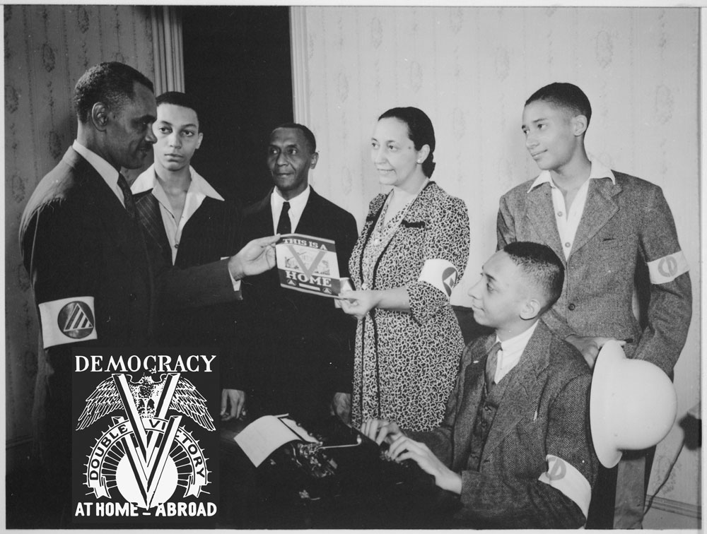 People hold a poster for the Double V campaign