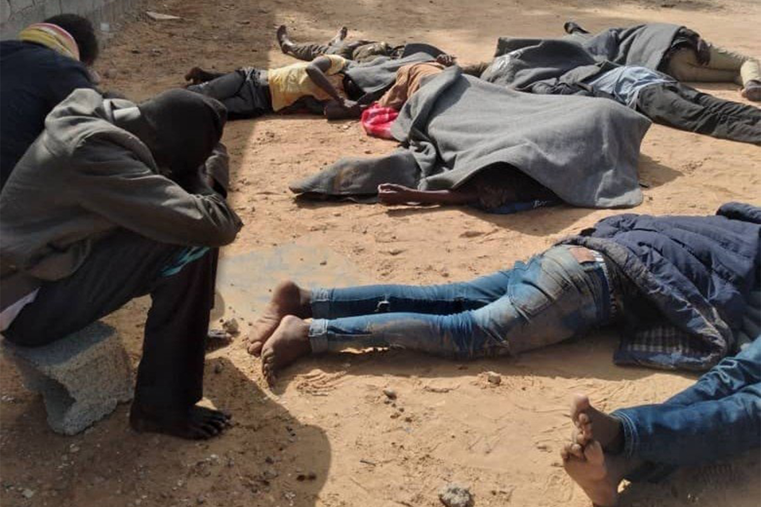 Several people lie on the floor in an outdoors space while on hunger strike.