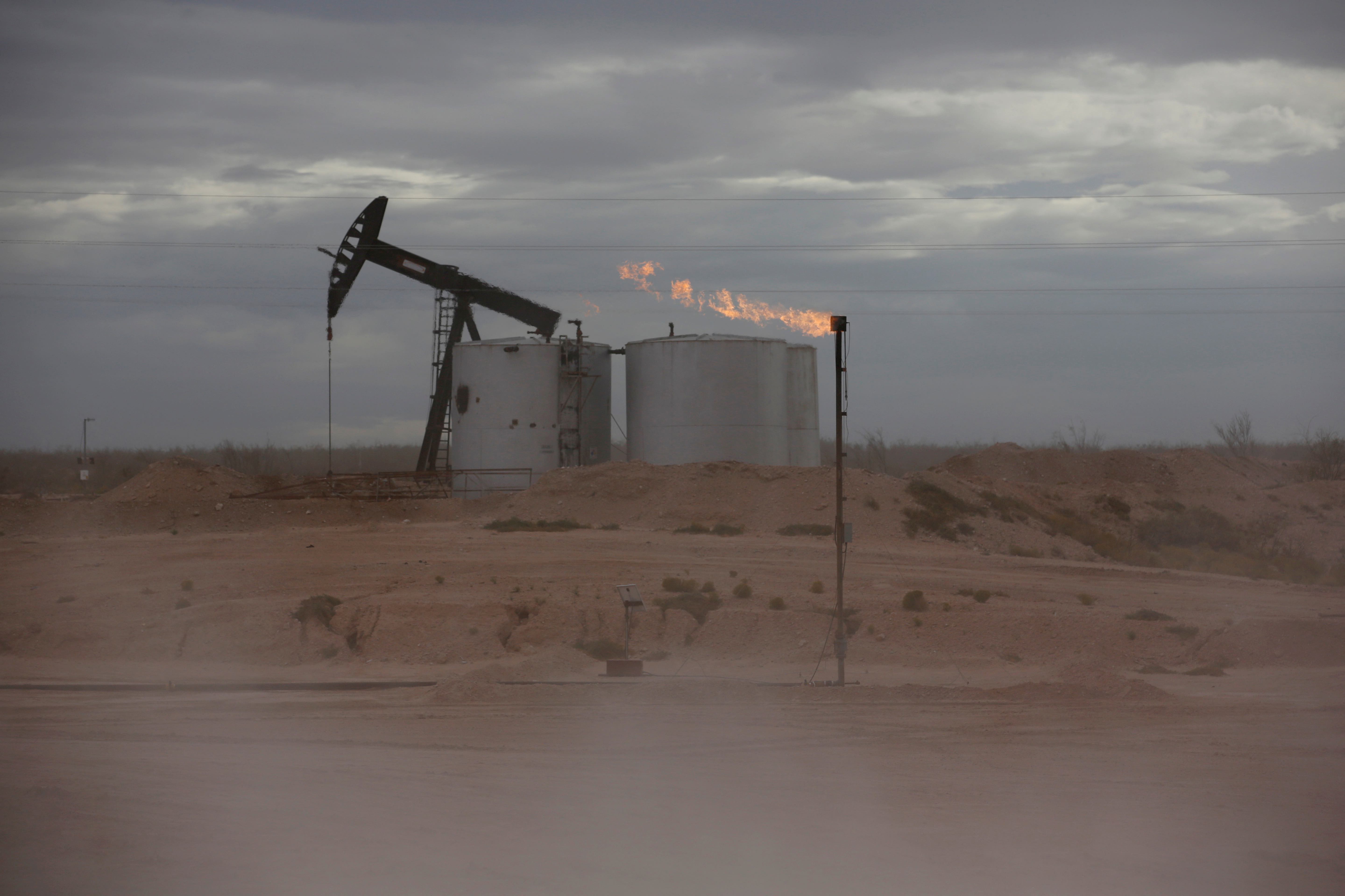 Dust blows around a crude oil pump jack