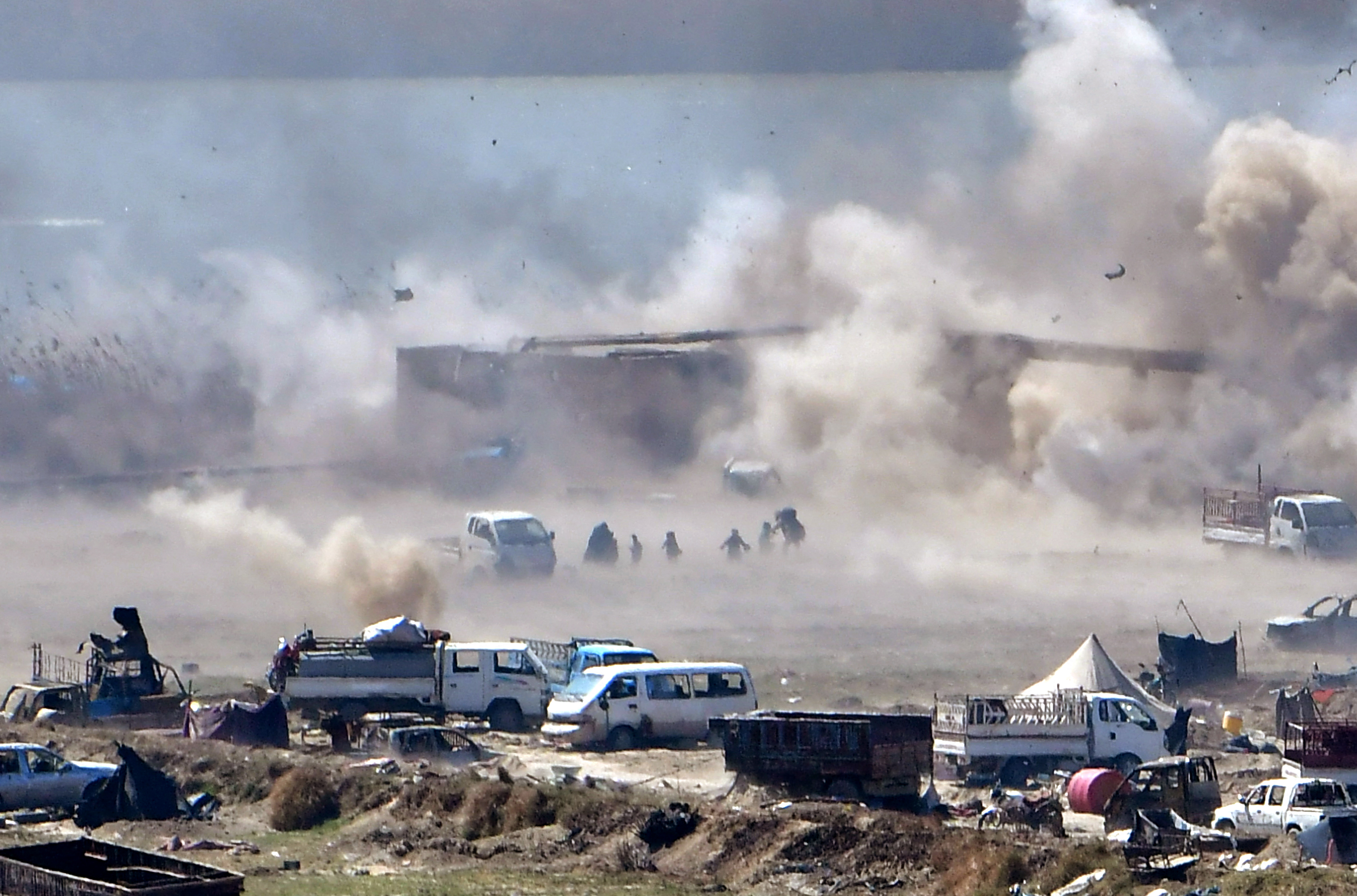 People are seen fleeing as heavy smoke rises above the Islamic State (IS) group's last remaining position in the village of Baghouz