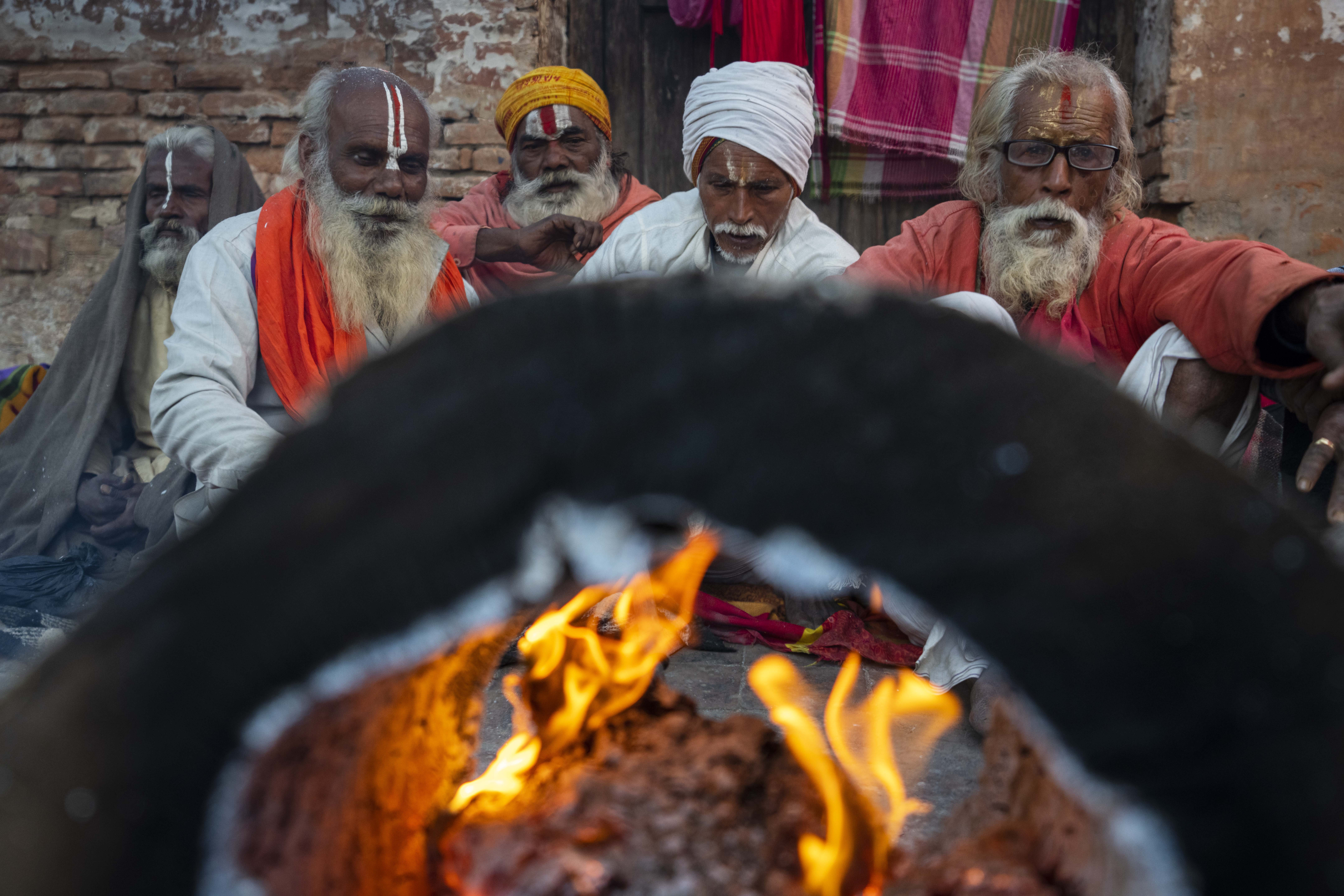 Holy men from India warm themselves sitting next to a bonfire