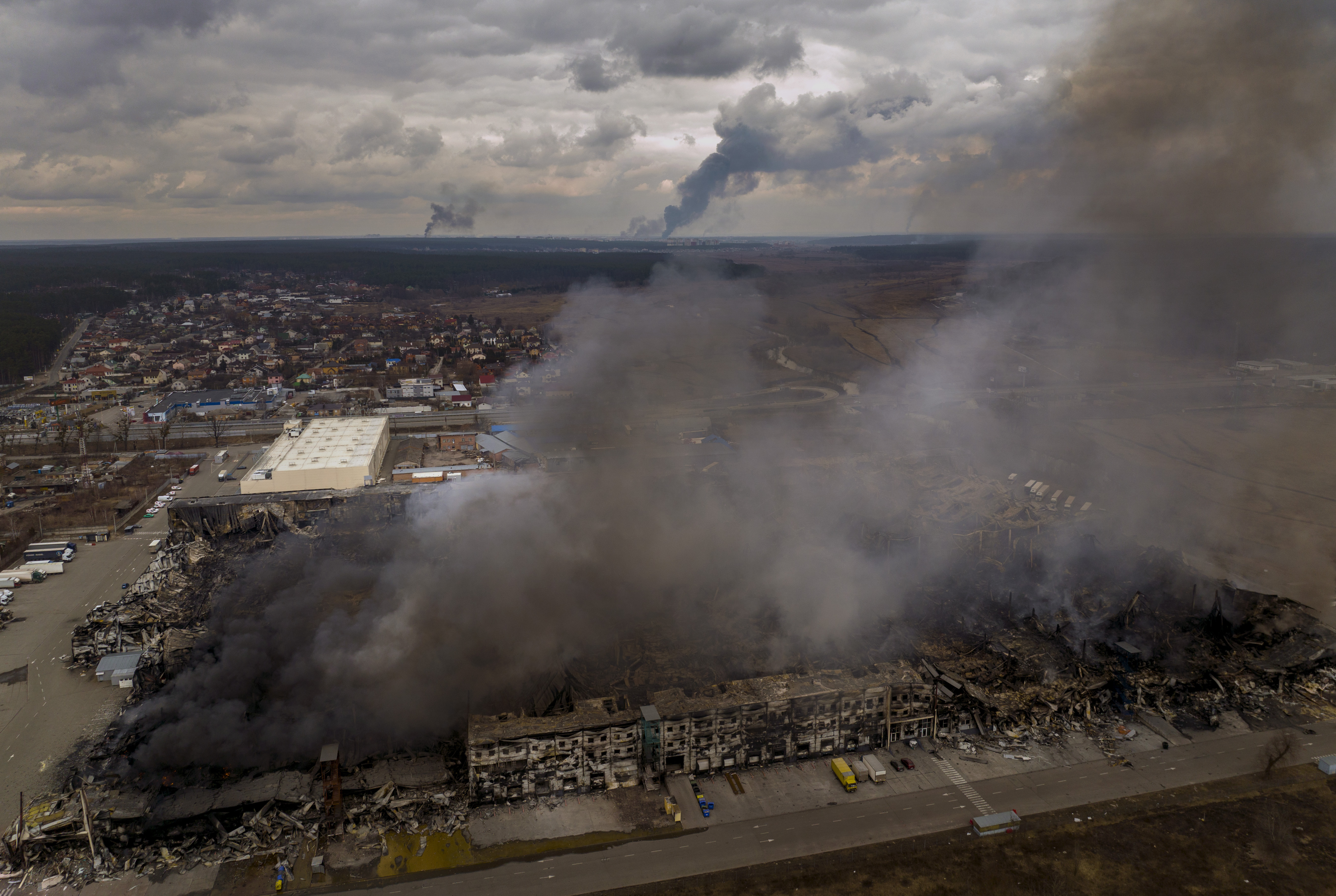 A factory and a store burn after having been bombarded in Irpin
