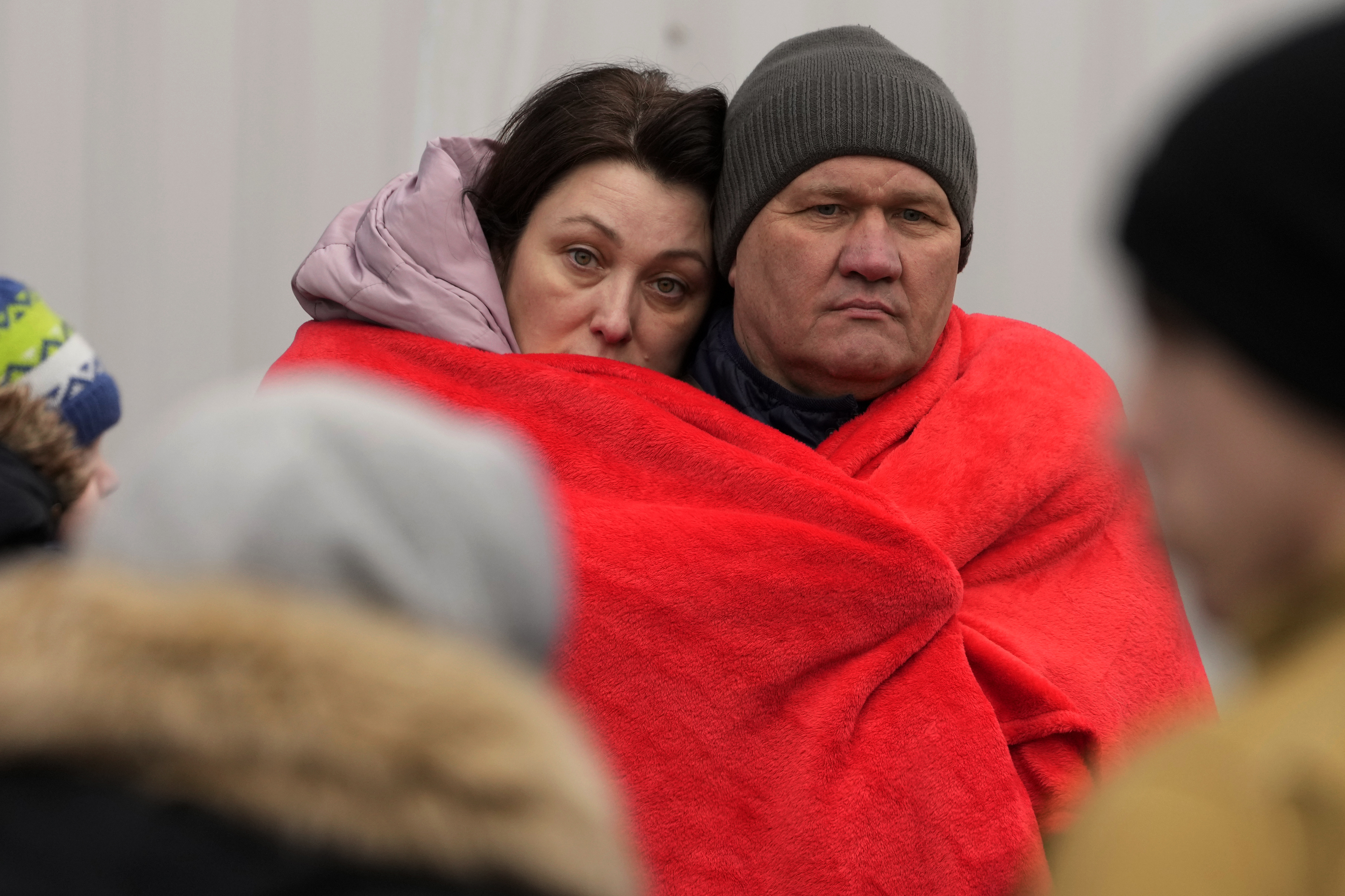 Refugees that fled Ukraine from the war cover themselves with a blanket while they wait for a bus to leave Korczowa border crossing, Poland