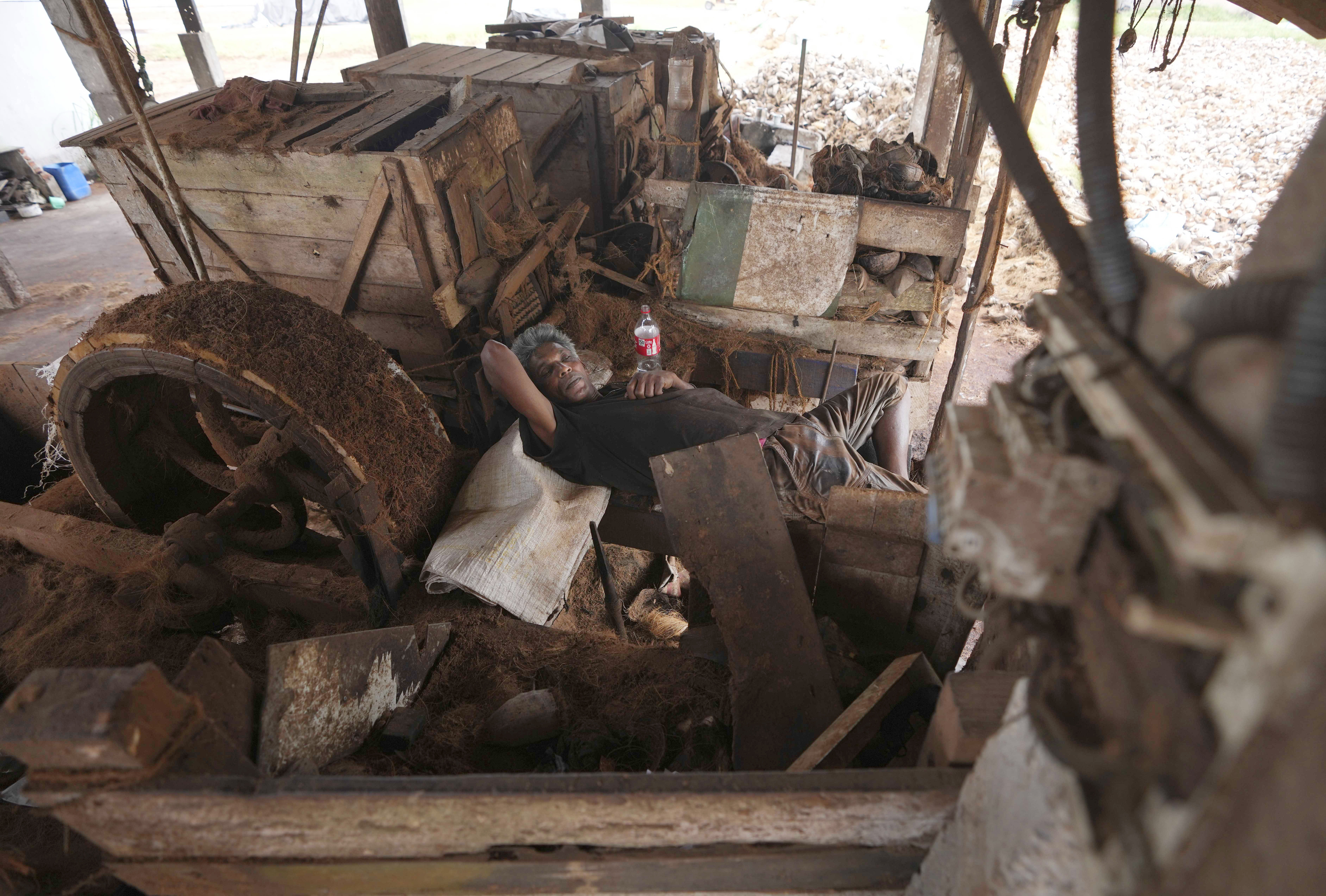 A Sri Lankan coir mill worker takes a nap at an idle production line during a power cut