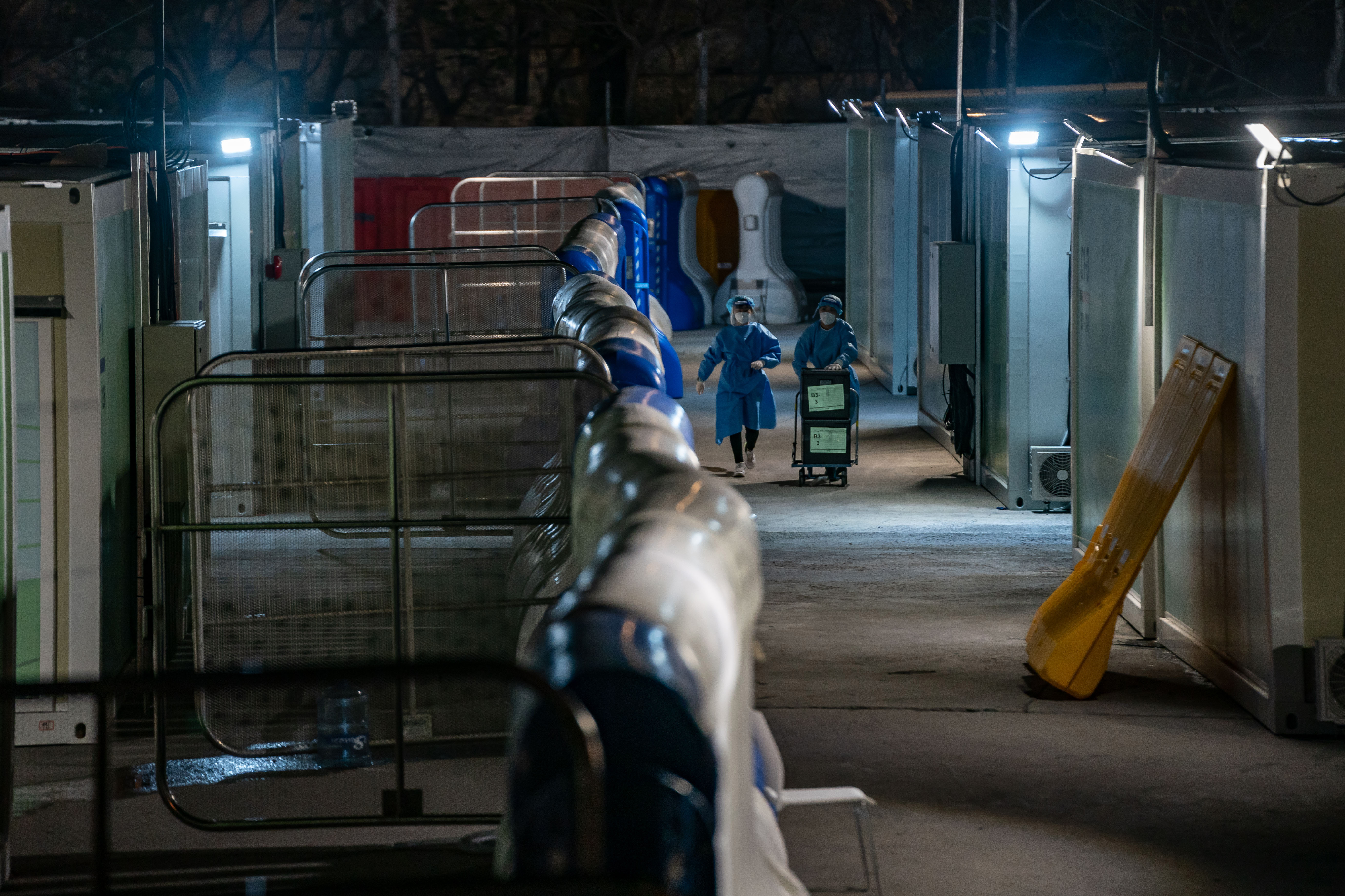 Healthcare workers walk down dark corridor at a temporary isolation facility for COVID-19