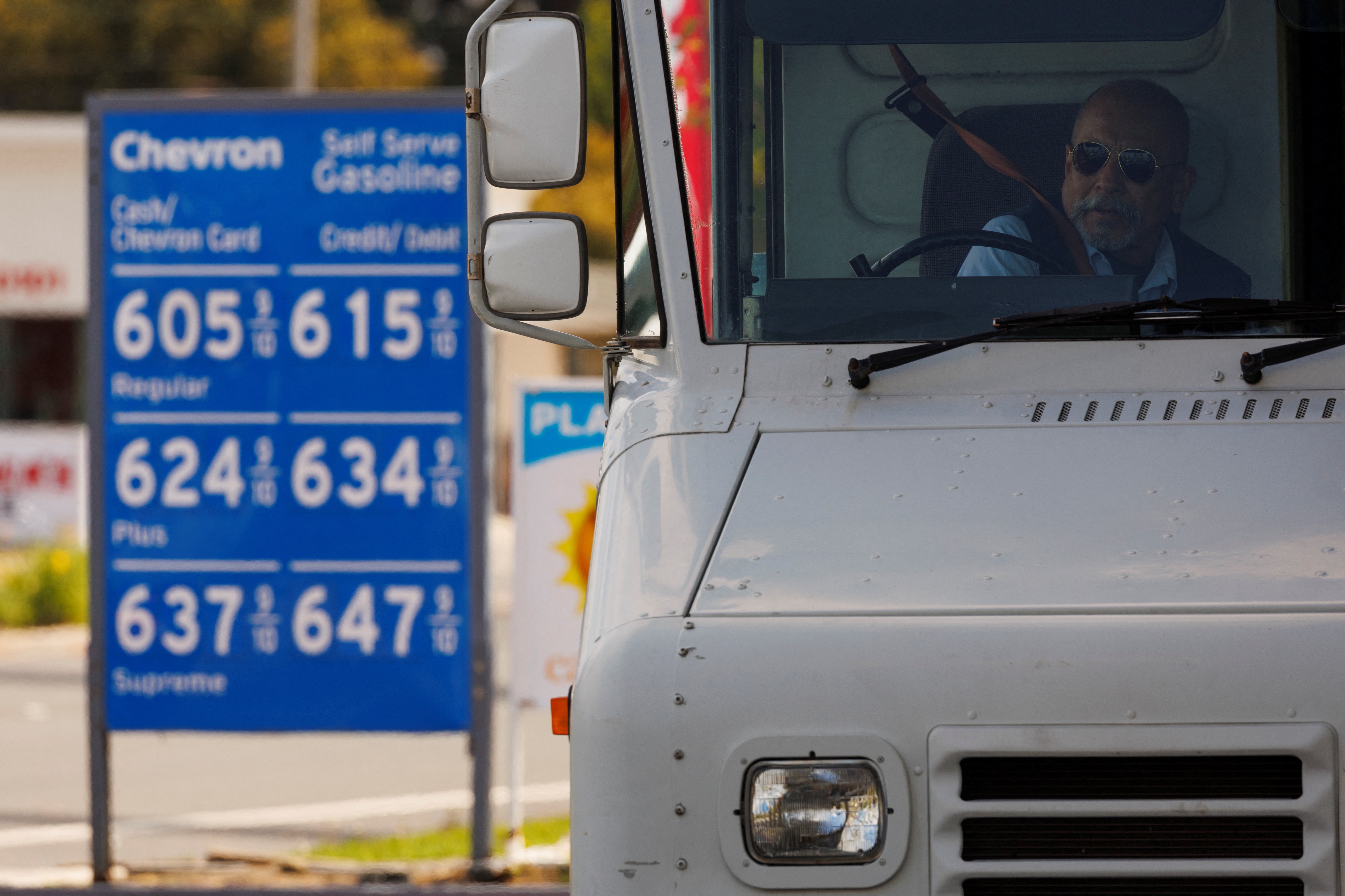 A U.S. postal worker puts his seatbelt on after filing up his vehicle at a gas station in Garden Grove, California, U.S
