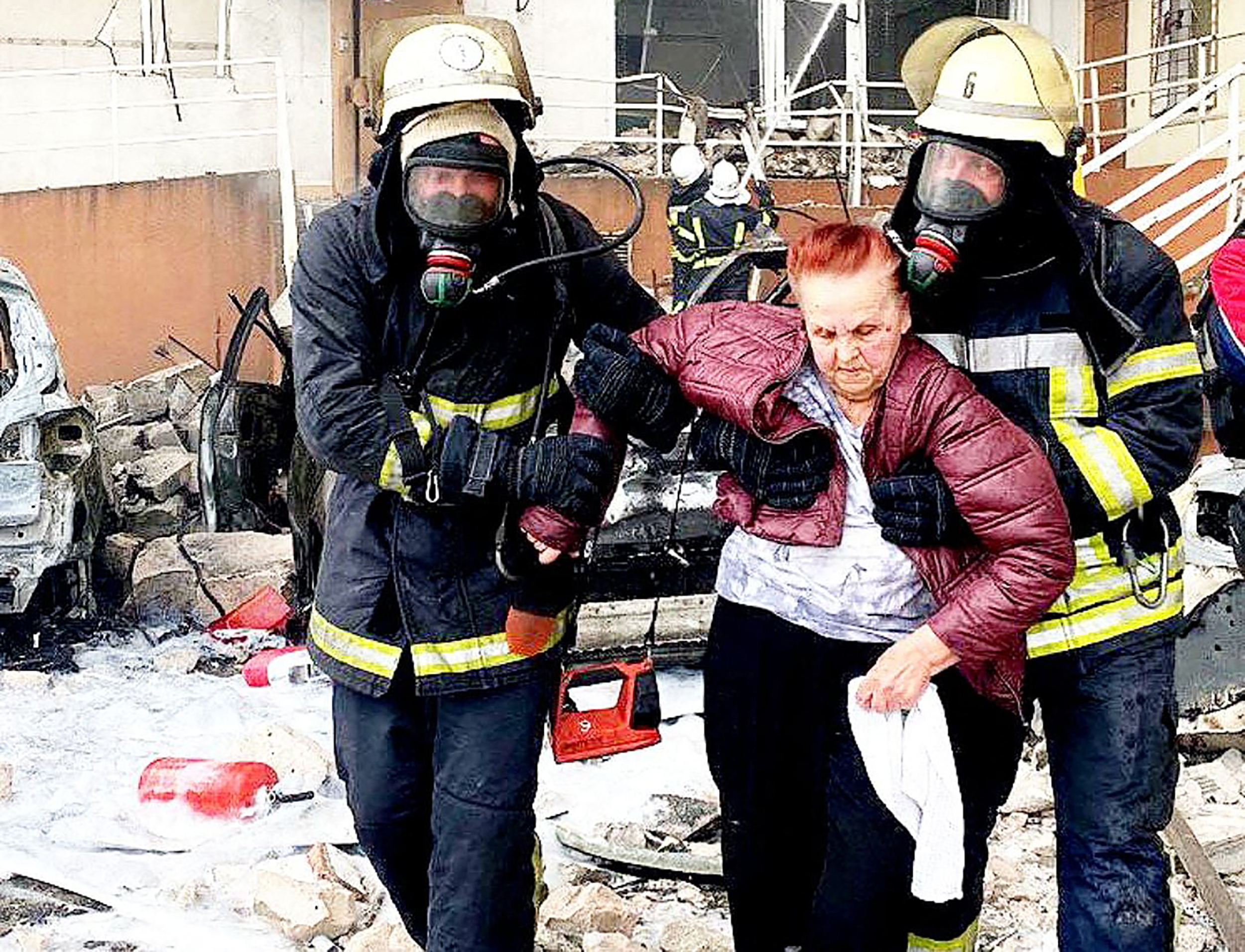 rescuers carrying a woman out of a damaged building