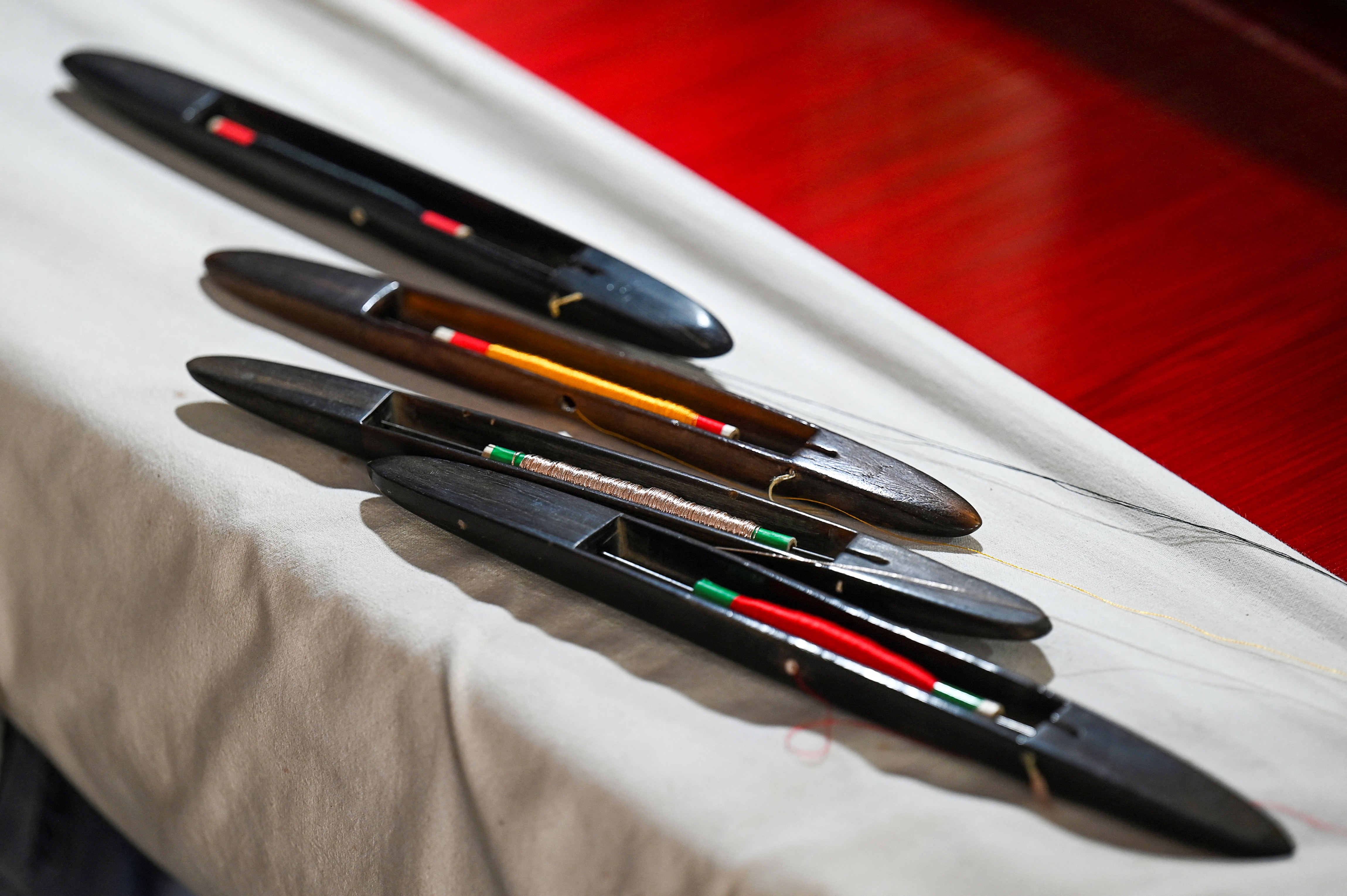 threads of various colours are kept near a hand loom to weave a traditional Banarasi silk sari
