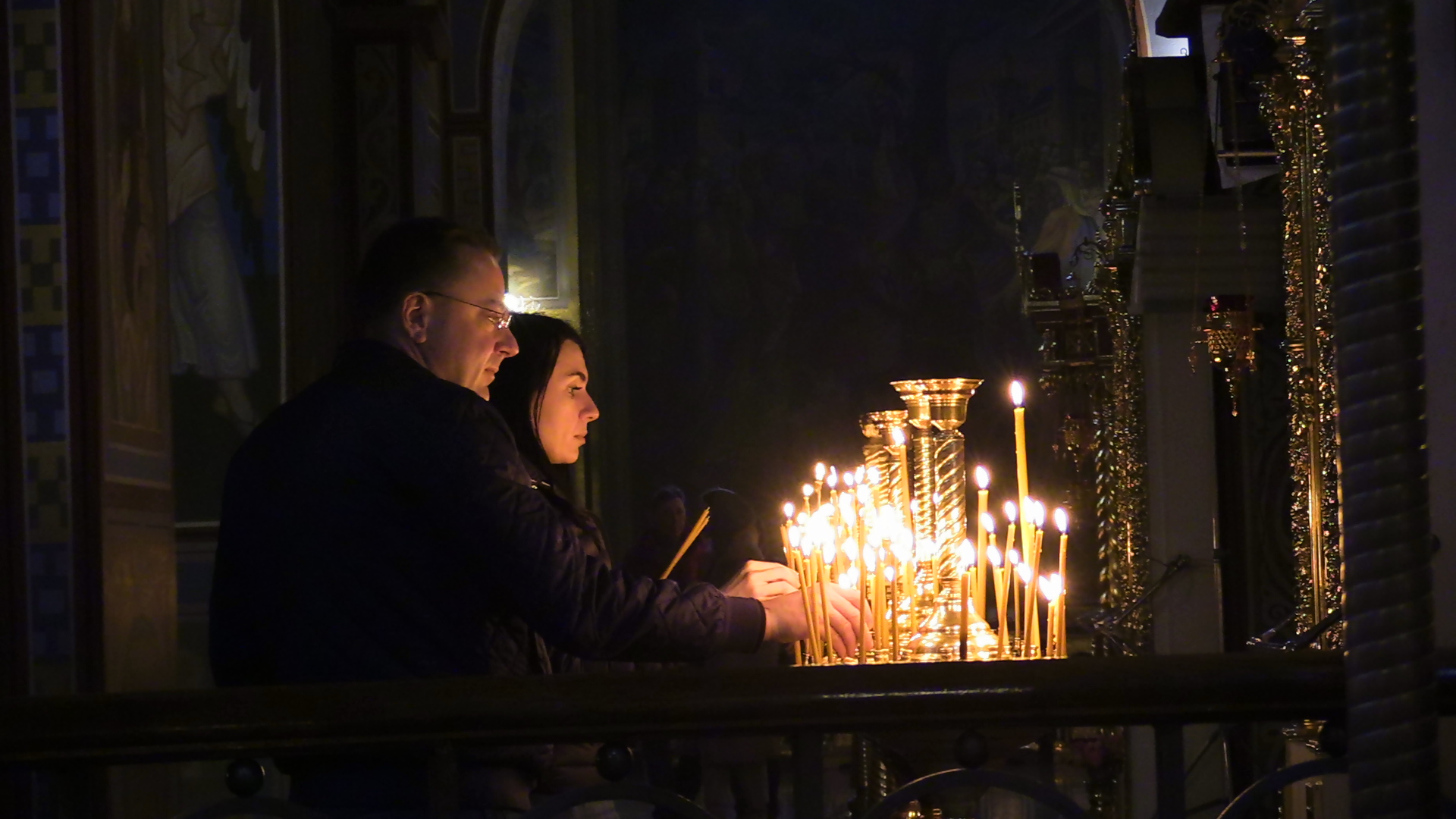 A Ukrainian couple lights candles on Holy Saturday in St. Michael's Monastery in Kyiv [Mansur Mirovalev/Al Jazeera]