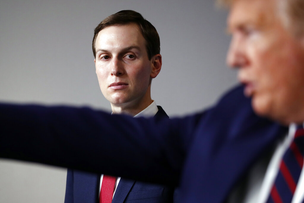 Donald Trump speaks and gestures as Jared Kushner looks on