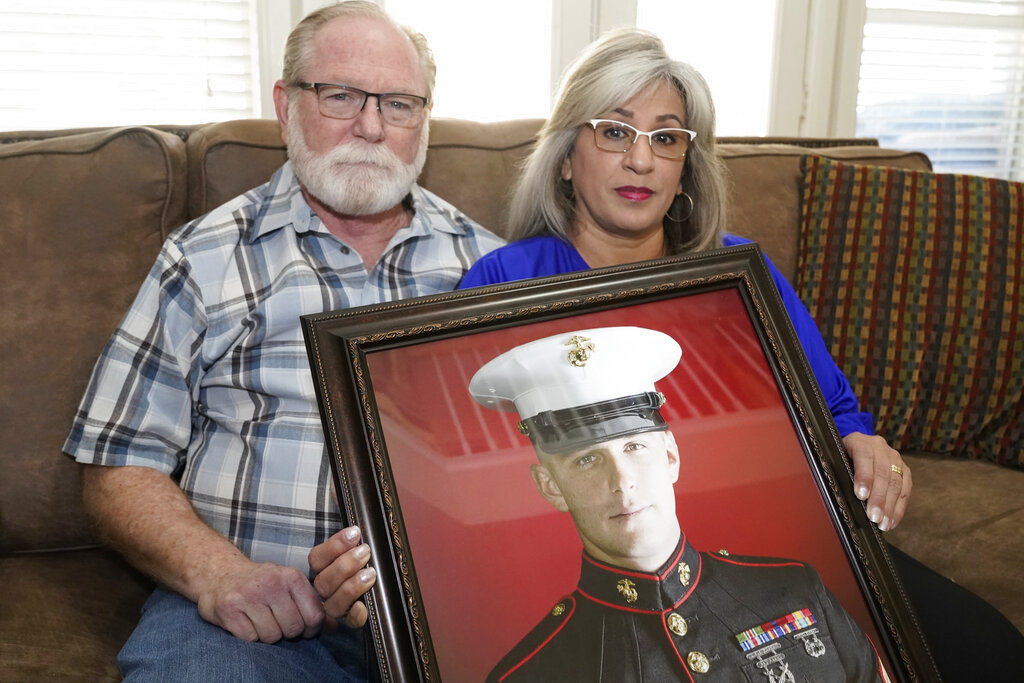 Joey and Paula Reed pose for a photo with a portrait of their son Marine veteran and Russian prisoner Trevor Reed at their home in Fort Worth, Texas.