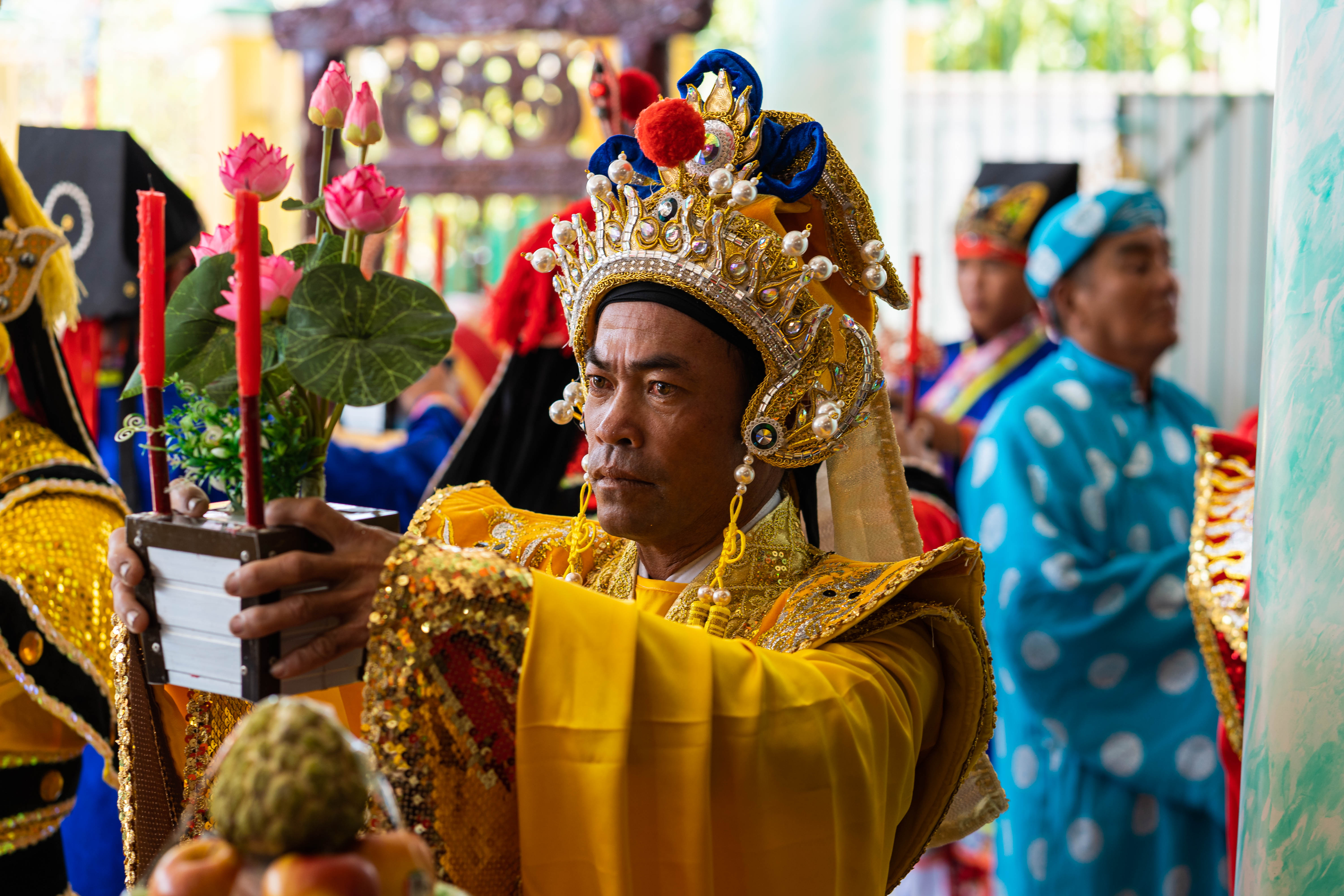 A photo of whale worshippers in elaborate dress carrying candles and flowers as part of a co-ordinated ritual during Phuoc Hai’s whale worship festival.