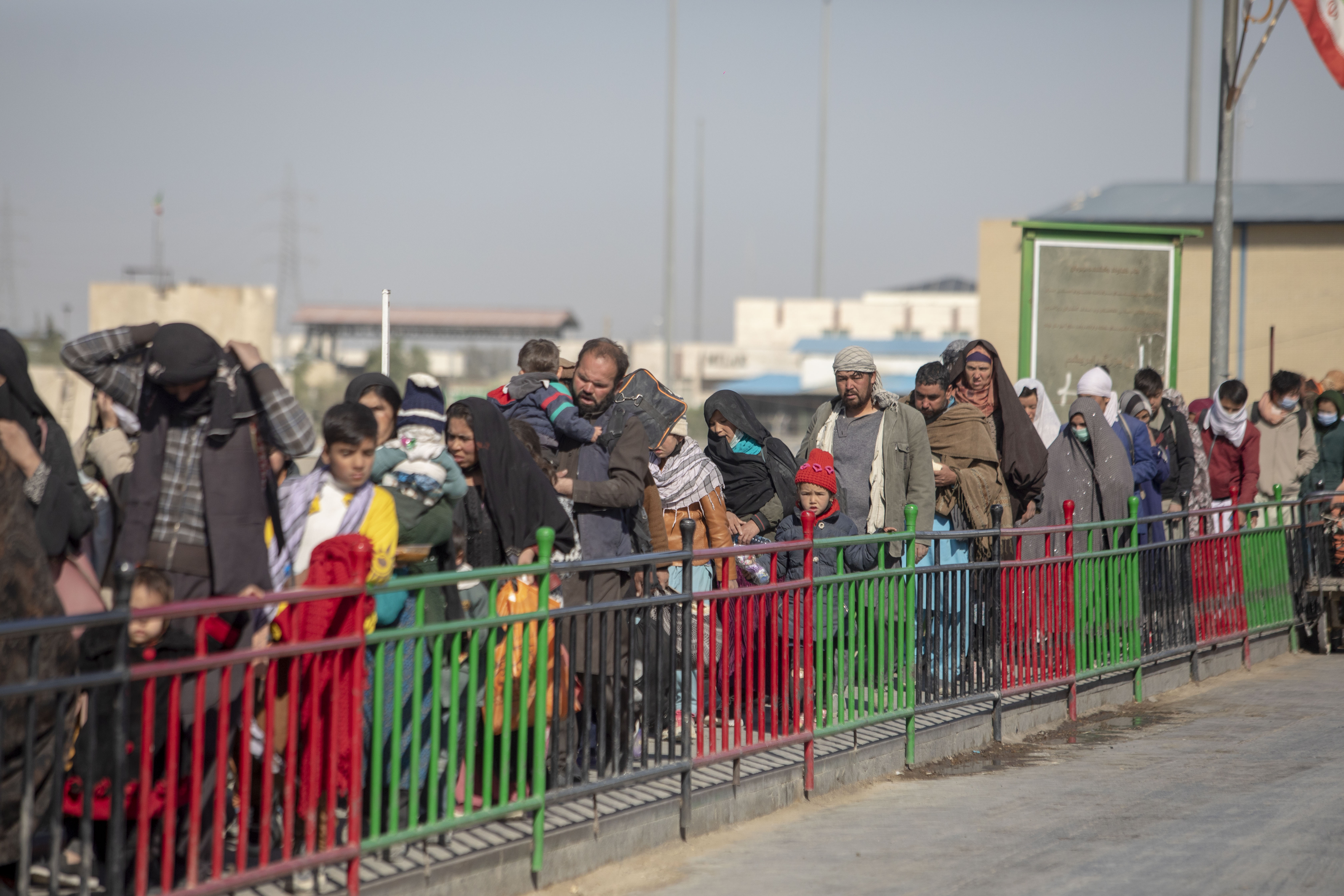 Afghans wait in a queue at the Afghanistan-Iran border