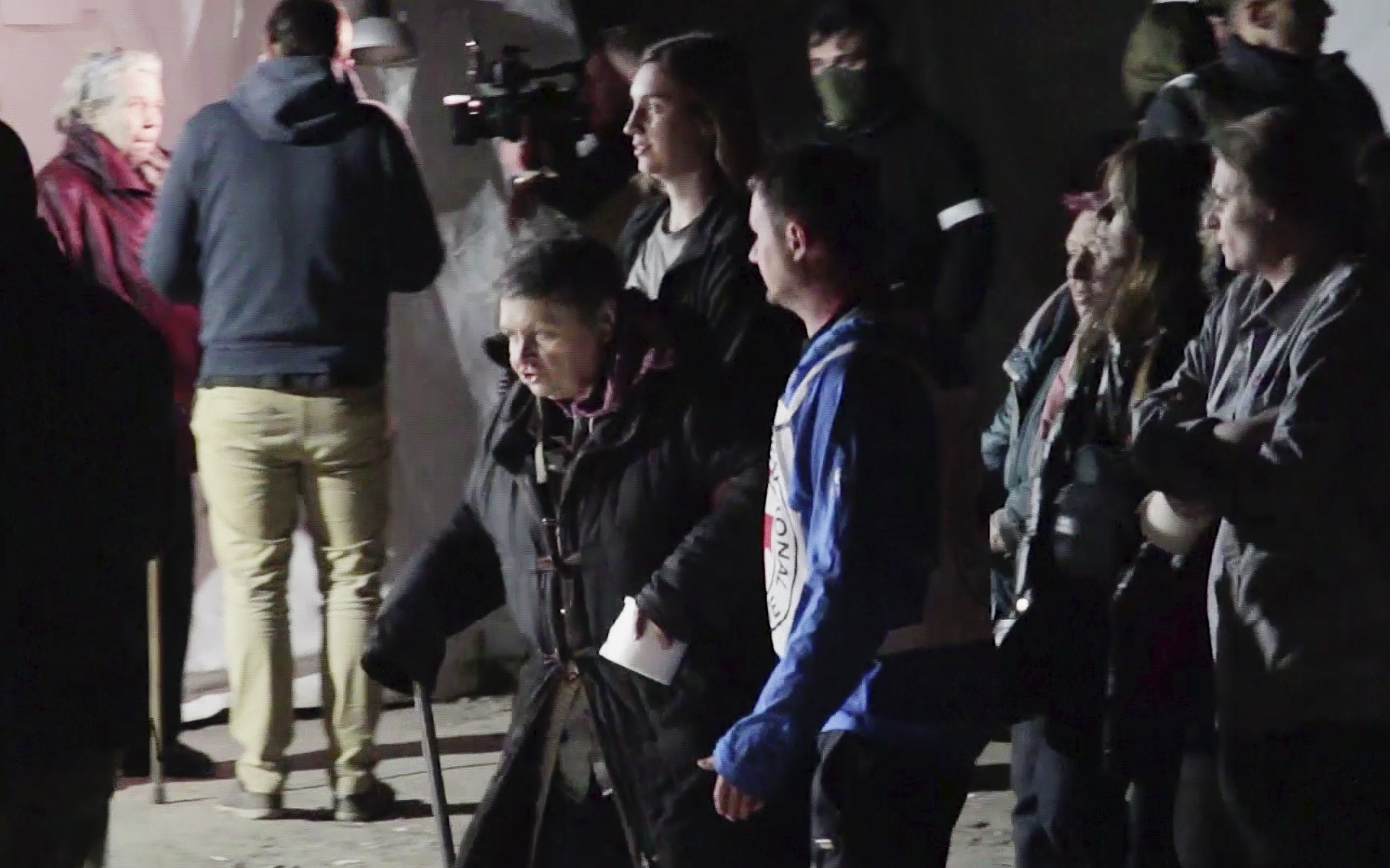 Civilians evacuated from Azovstal steel plant accompanied by Red Cross personnel walk in an area controlled by Russian-backed separatist forces in Bezimenne, about 20 kilometres (12 miles) east of Mariupol.