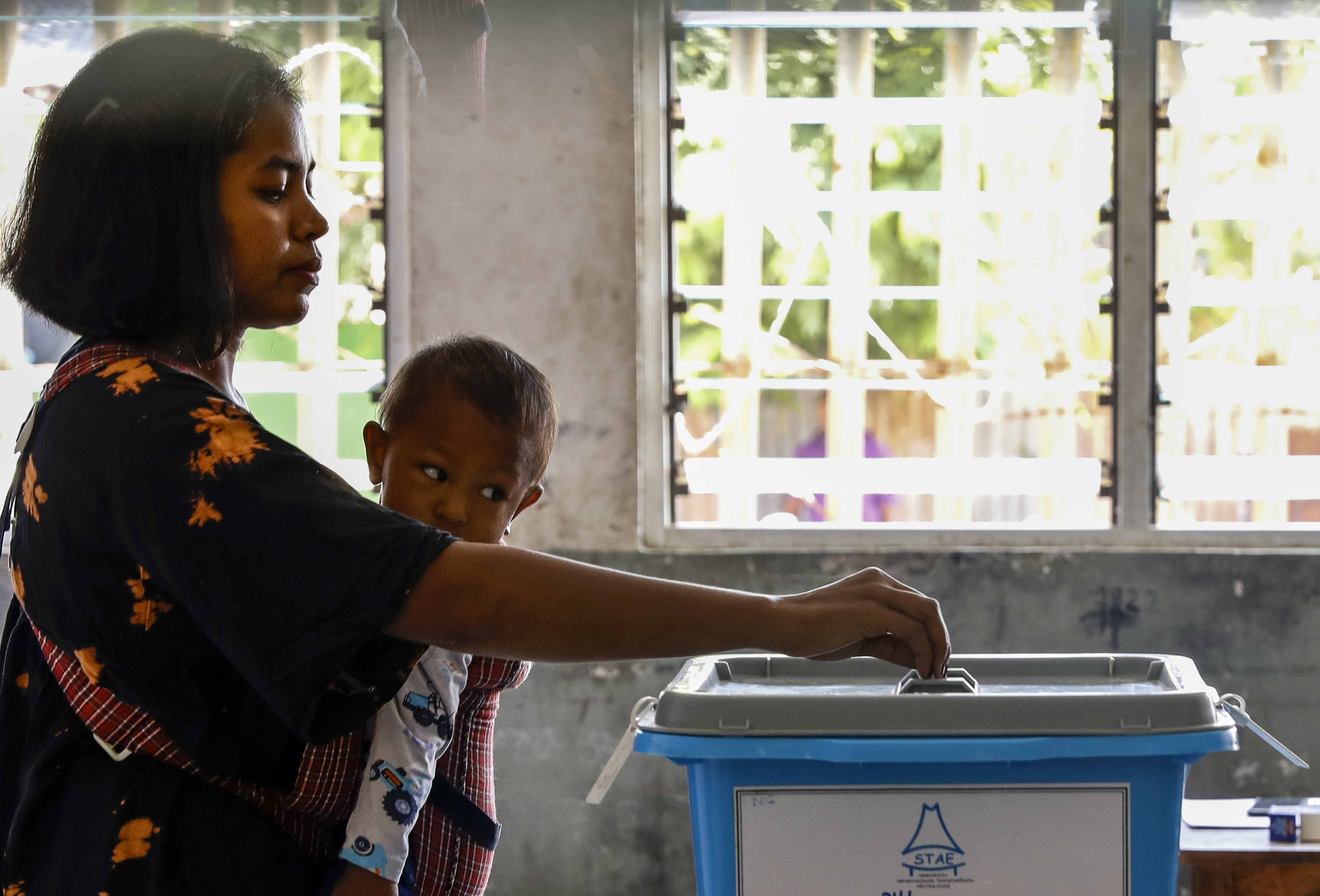 A woman casts her vote in TImor Leste's election while holding her child