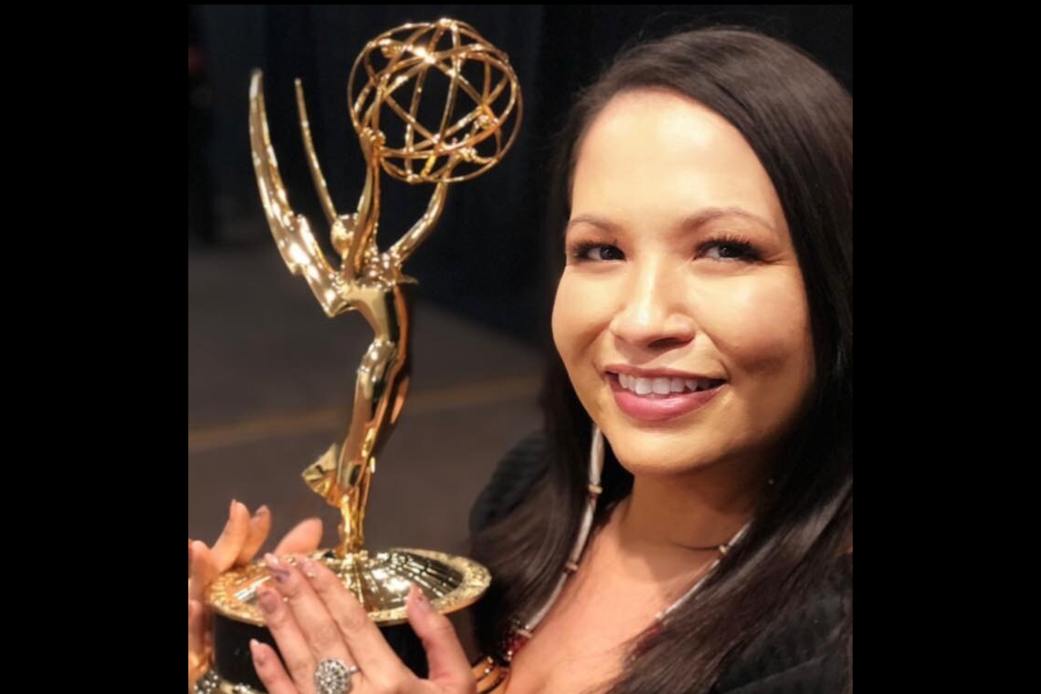 A photo of Sarah Eagle Heart holding an award.