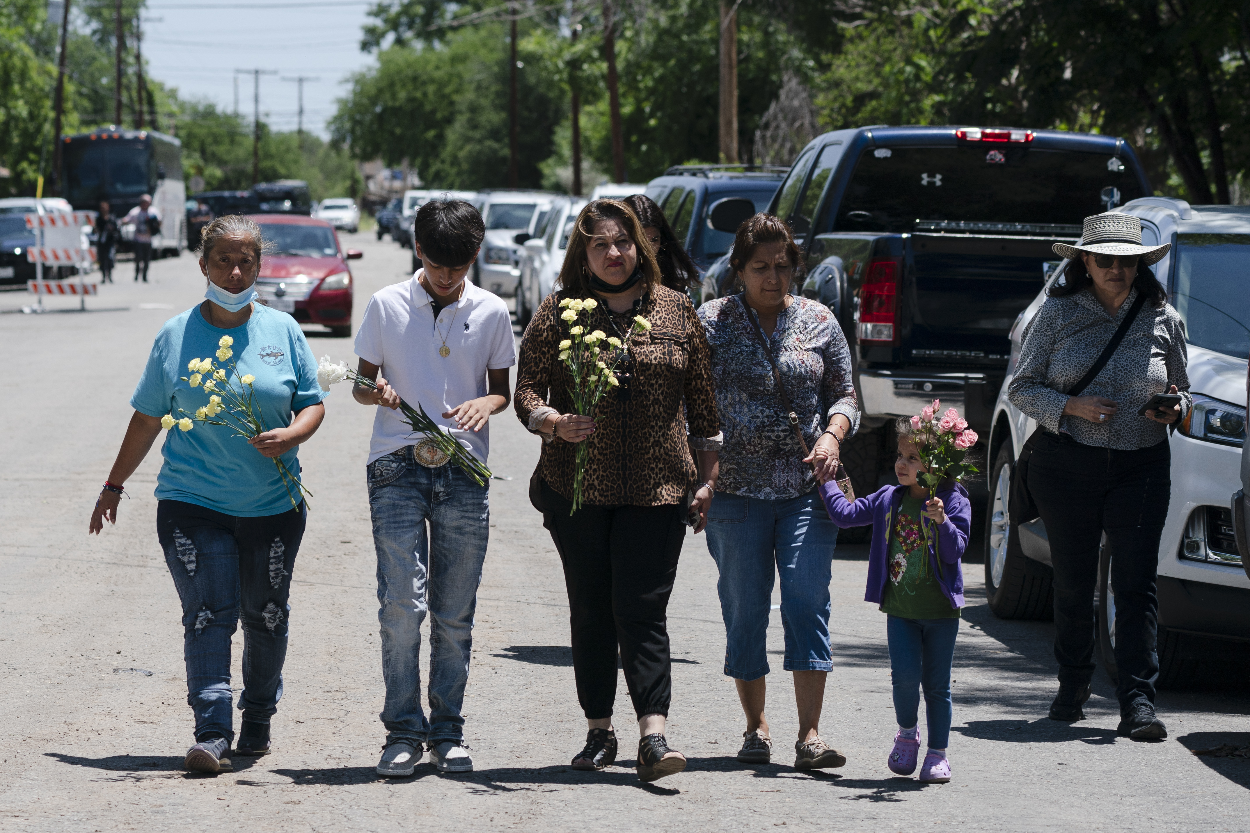 Victims' parents and relatives walking with flowers in hand.