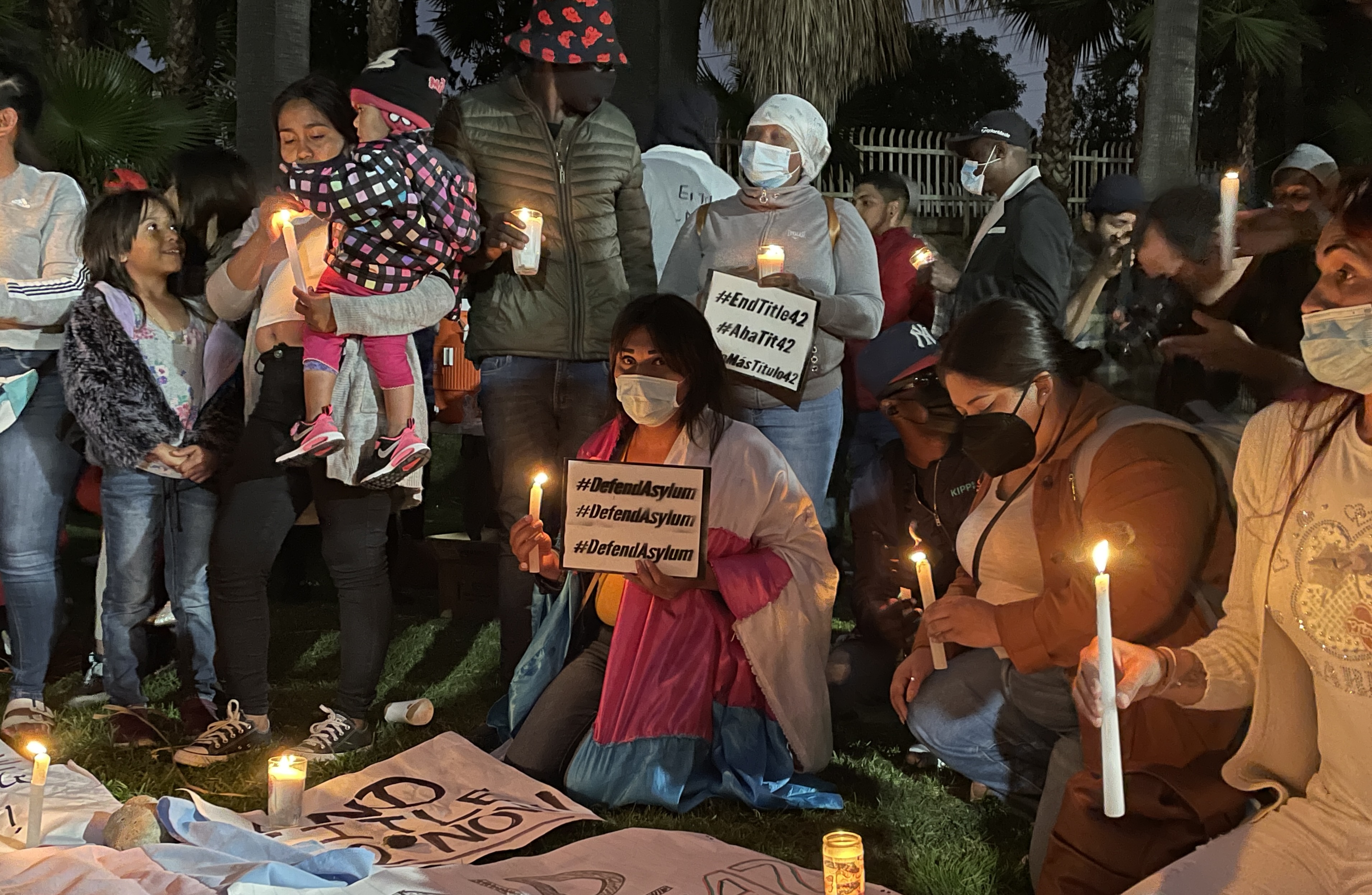 Patricia, a transgender asylum seeker, kneels on the grass during a vigil in Tijuana.