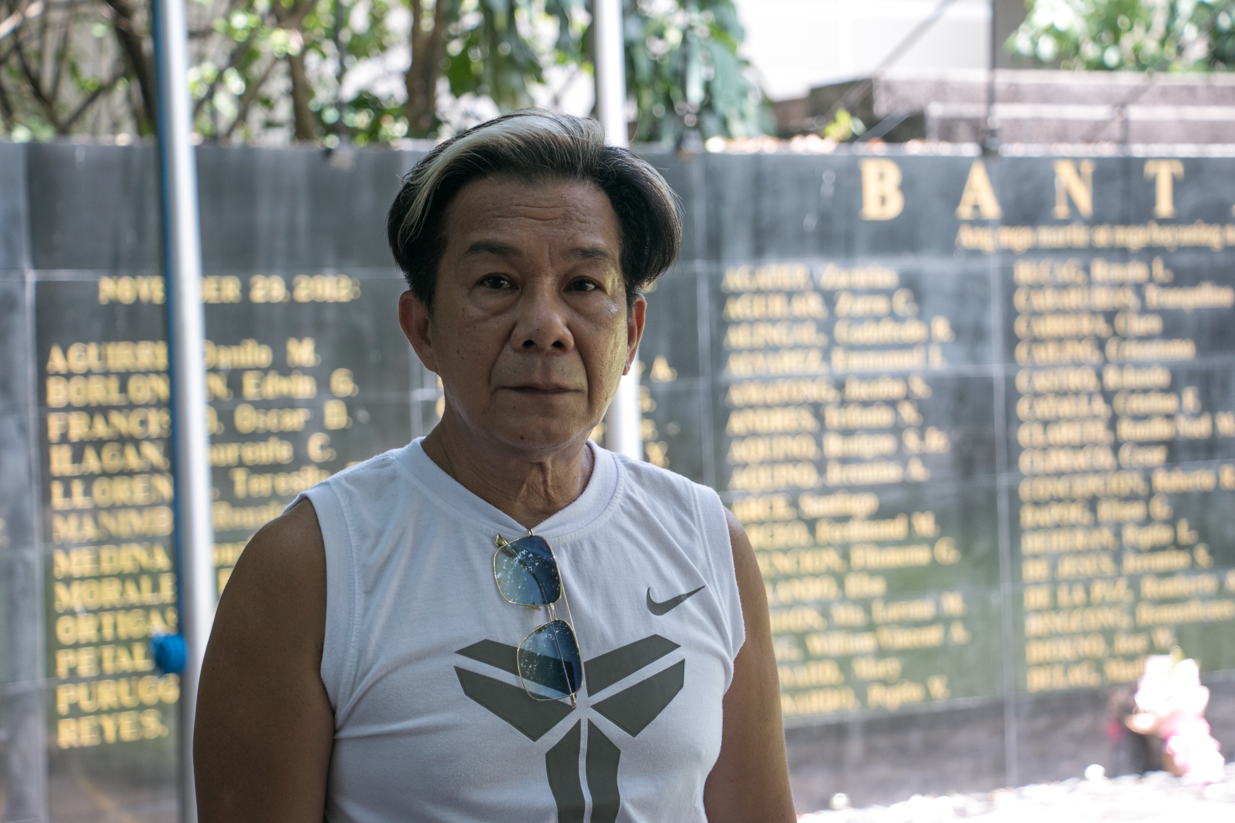 Joey Faustino standing in front of the memorial wall to the victims of Martial Law