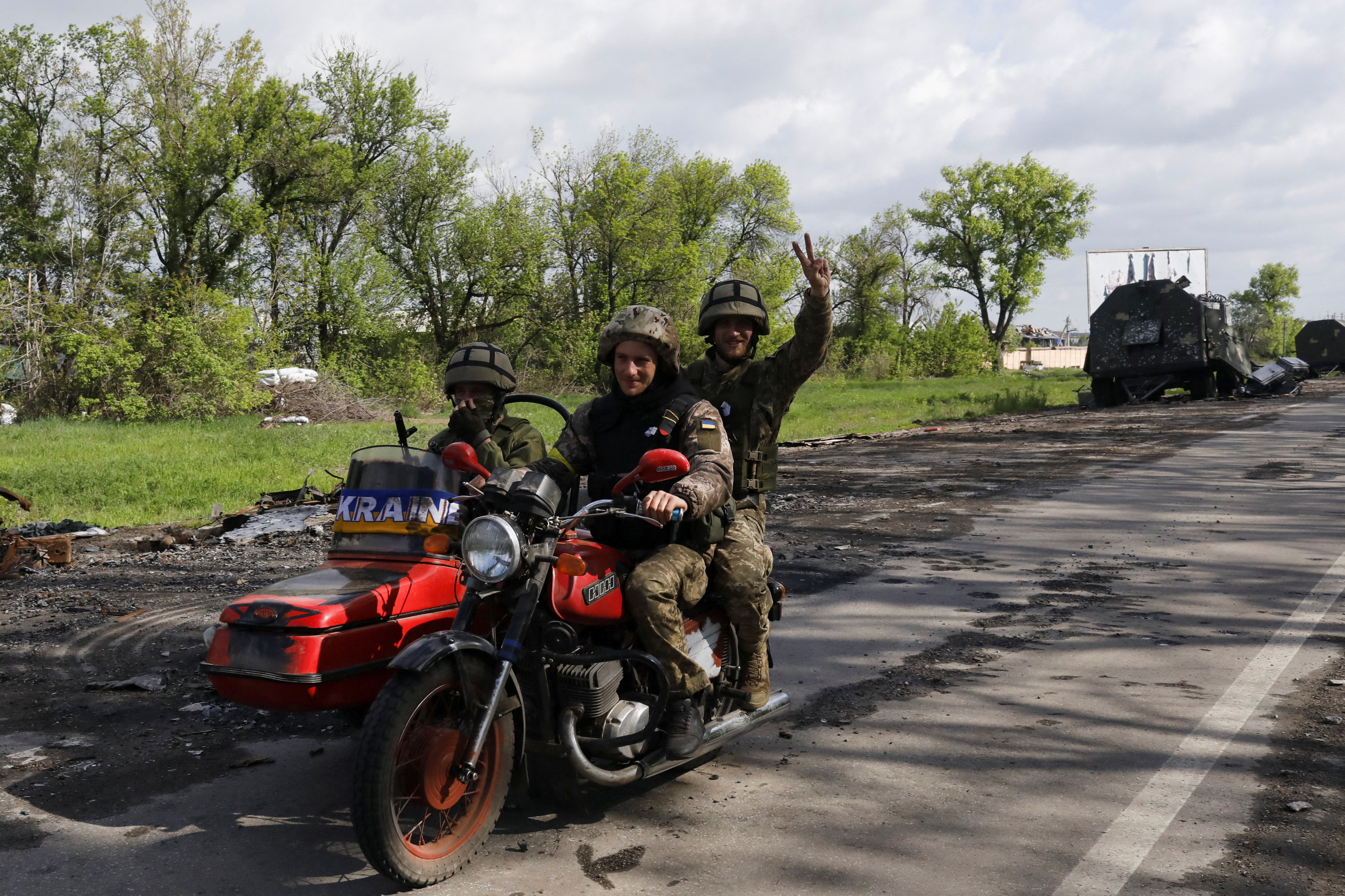 Ukrainian servicemen ride a motorcycle