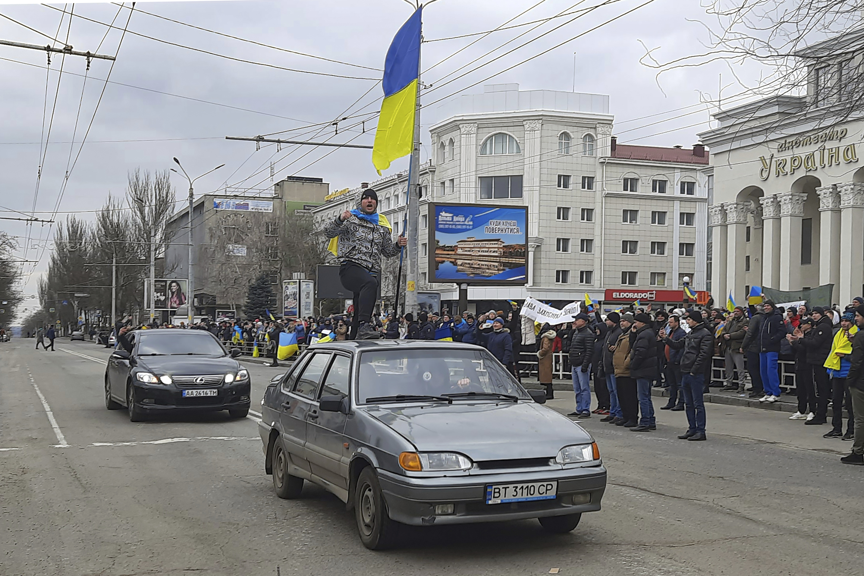 A man stands atop of a car with a Ukrainian flag during a rally against the Russian occupation in Svobody (Freedom) Square in Kherson.