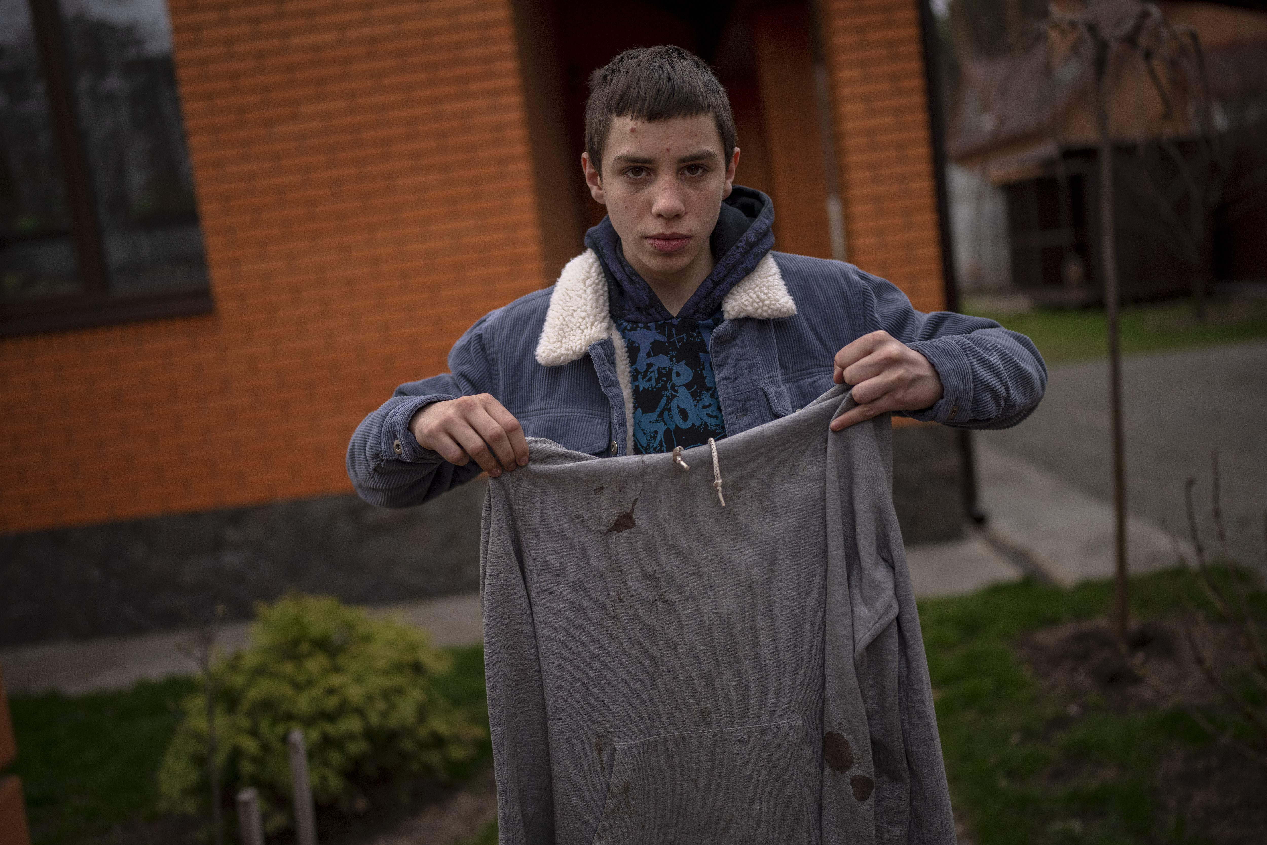 Yura Nechyporenko, 15, holds the hoodie he was wearing the day a Russian soldier tried to kill him in Bucha, on the outskirts of Kyiv, Ukraine, on Tuesday, April 19, 2022