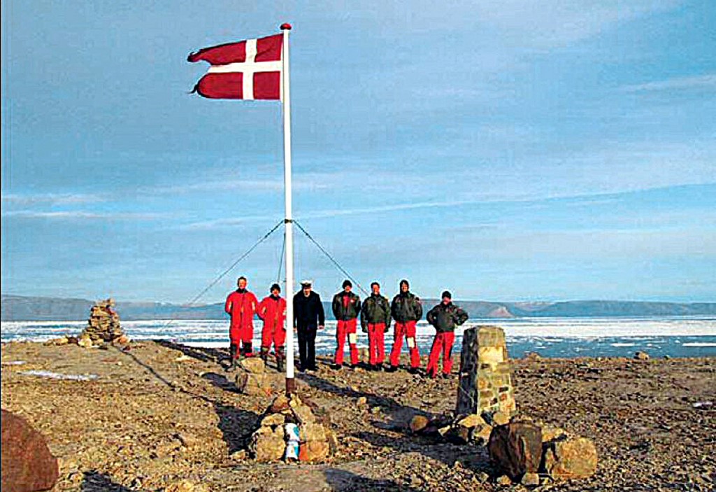 A group of Danish soldiers and the Danish flag stand on the Hans Island between Greenland and Canada