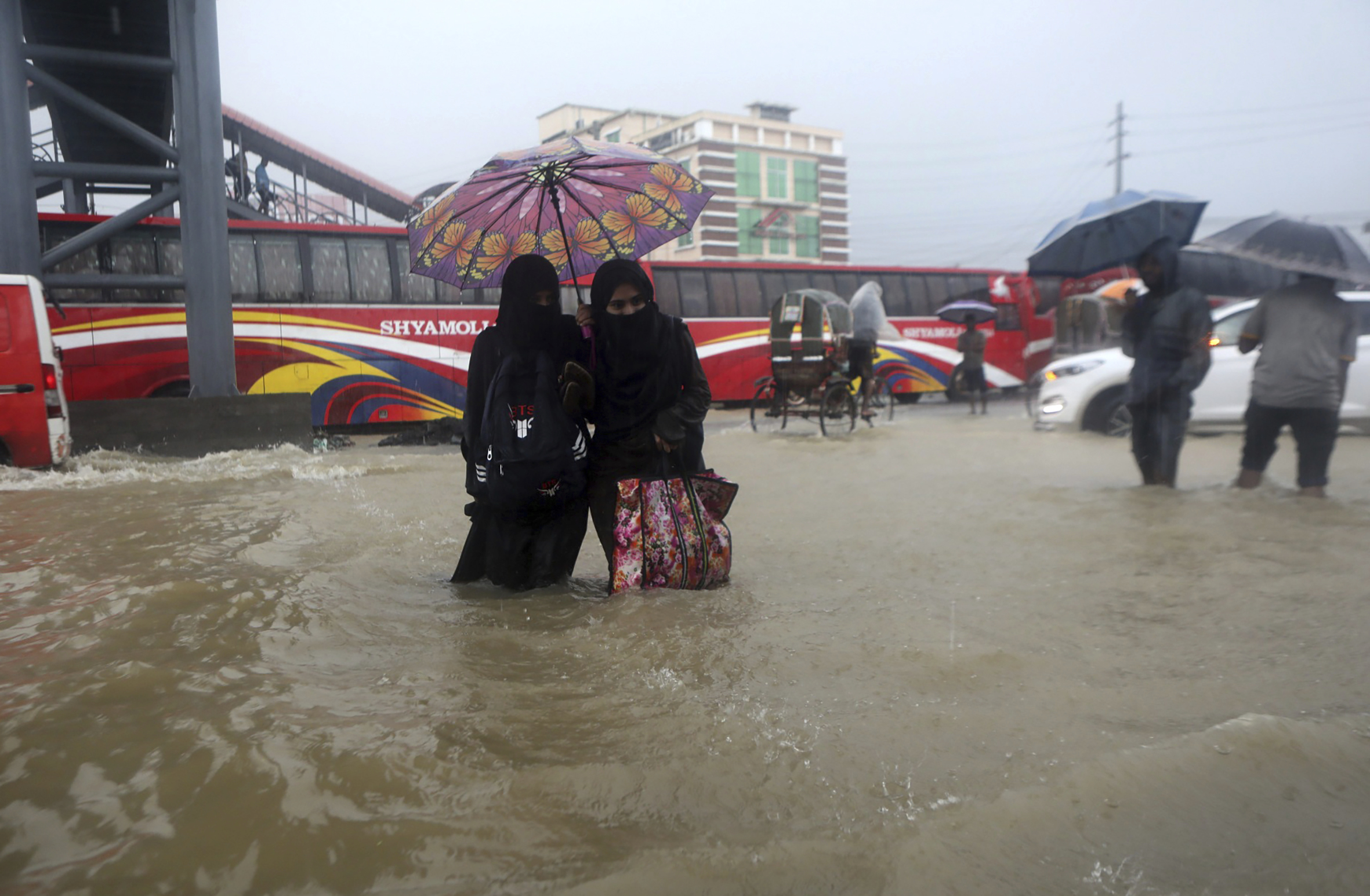 People wade through flooded waters in Sylhet