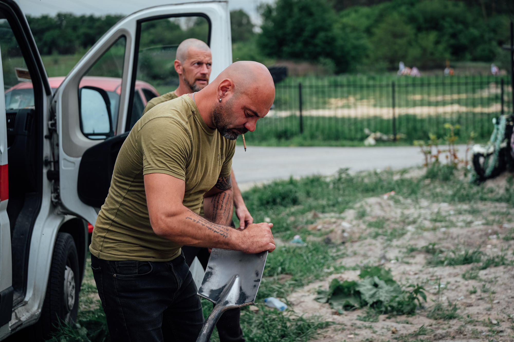 A photo of a man holding a spade with another man standing behind him.