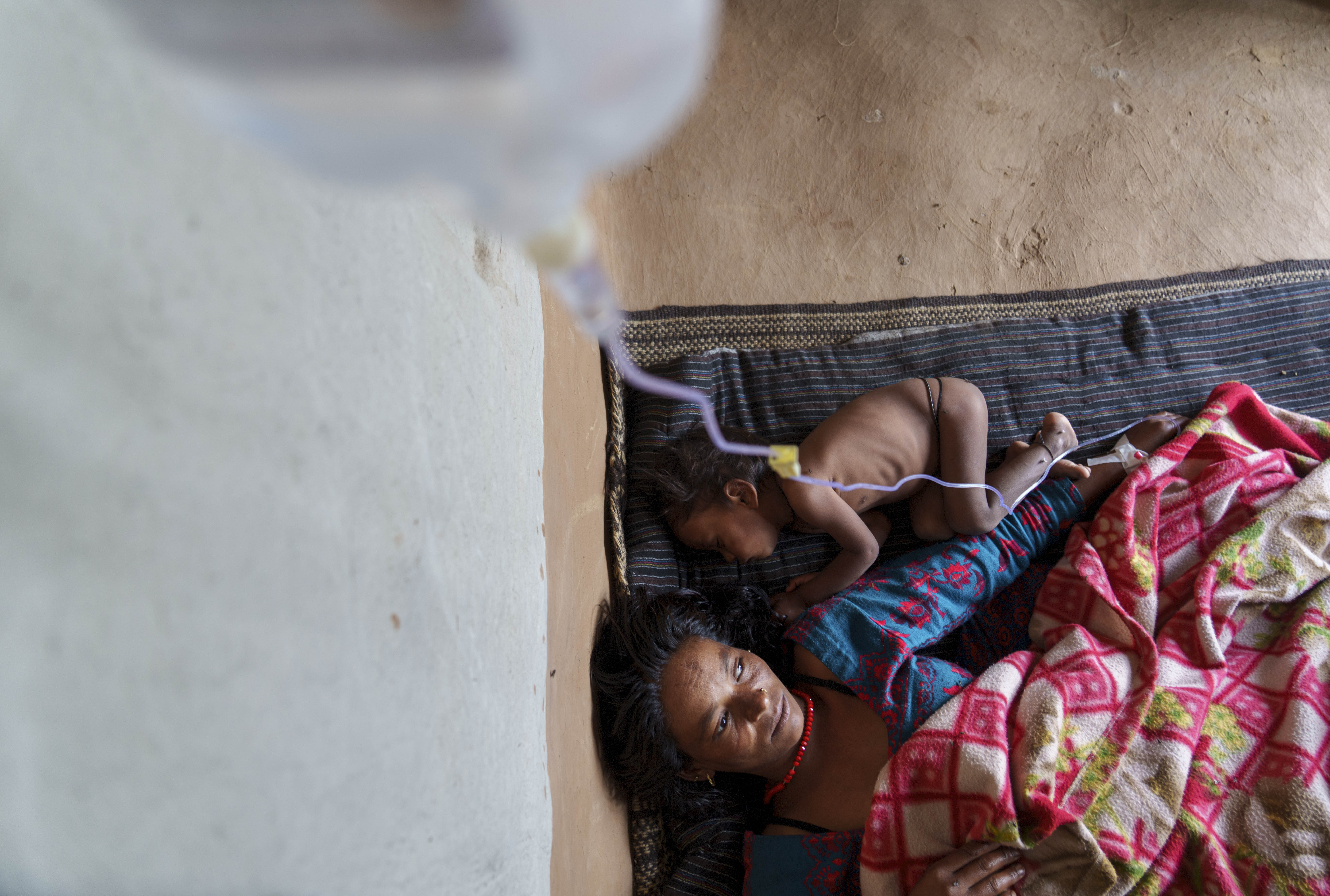 Nirmala Bishwokarma, 25 with her malnourished baby lie down at her home in Muktikot