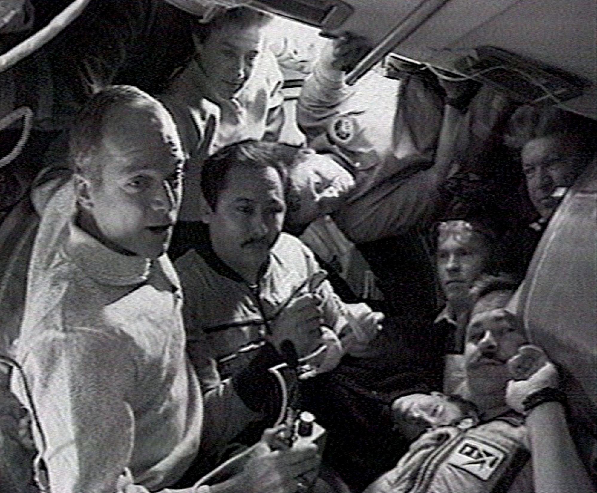 The crew members of Russian space station Mir and US shuttle Discovery pose for a picture during a video link and saying "goodbye" to each other. 