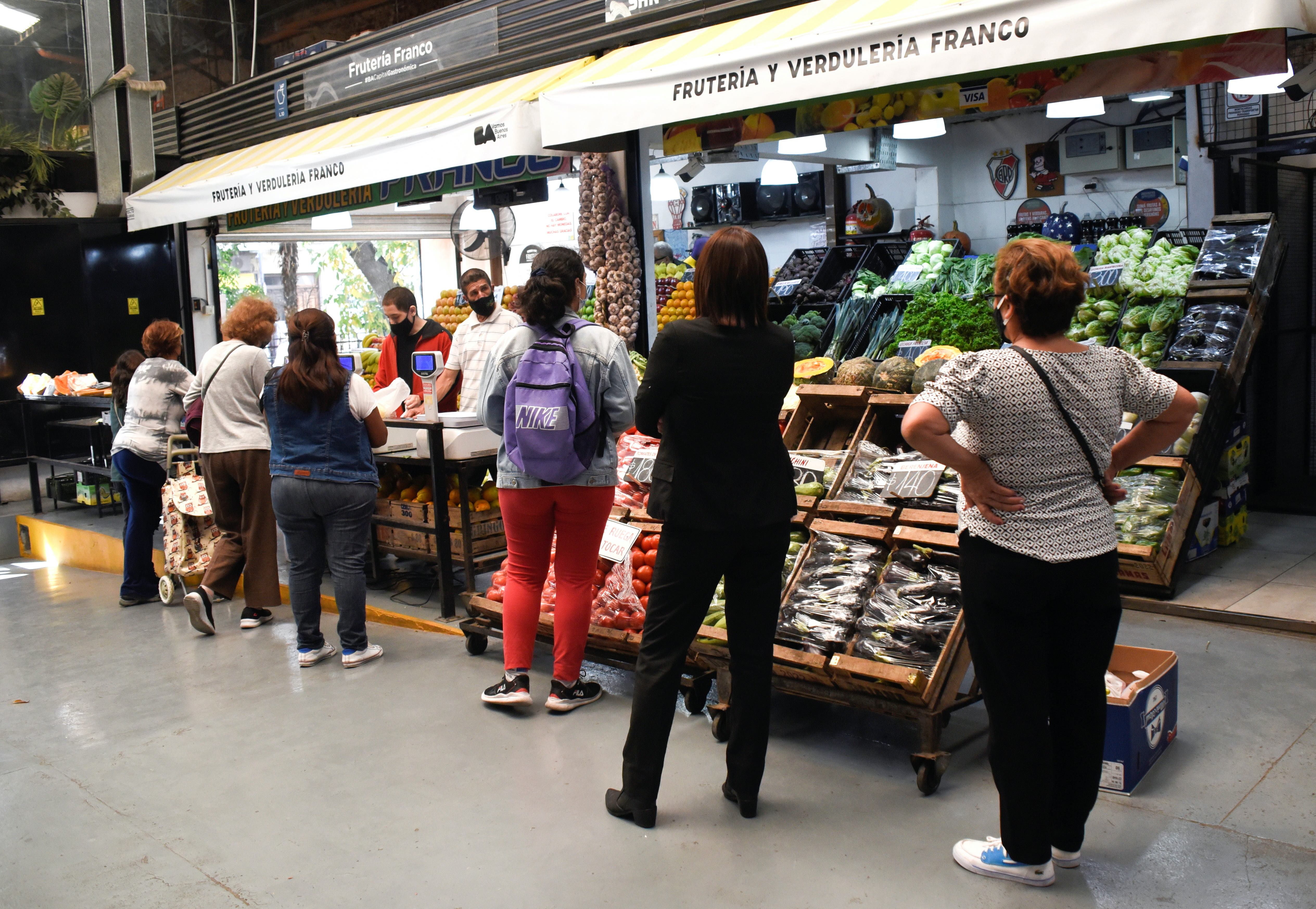 Customers line up to buy produce in a market as inflation in Argentina