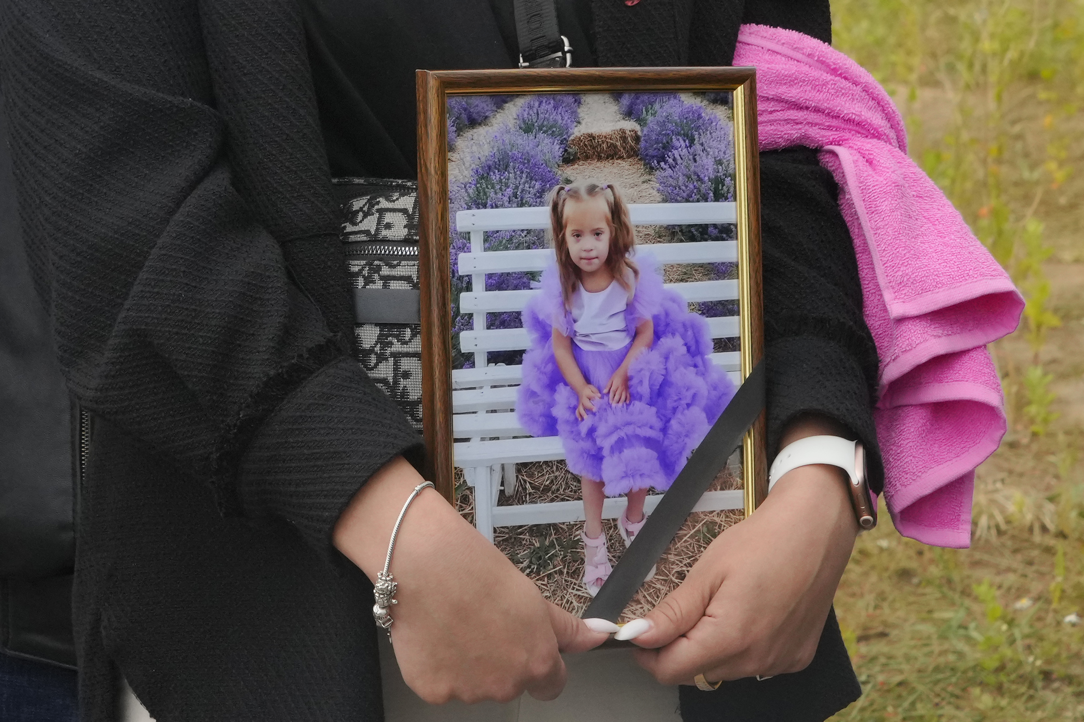A woman carries a portrait of Liza, 4-year-old girl killed by Russian attack, during a funeral ceremony in Vinnytsia, Ukraine, Sunday, July 17, 2022. Wearing a blue denim jacket with flowers, Liza was among 23 people killed, including two boys aged 7 and 8, in Thursday's missile strike in Vinnytsia. Her mother, Iryna Dmytrieva, was among the scores injured.