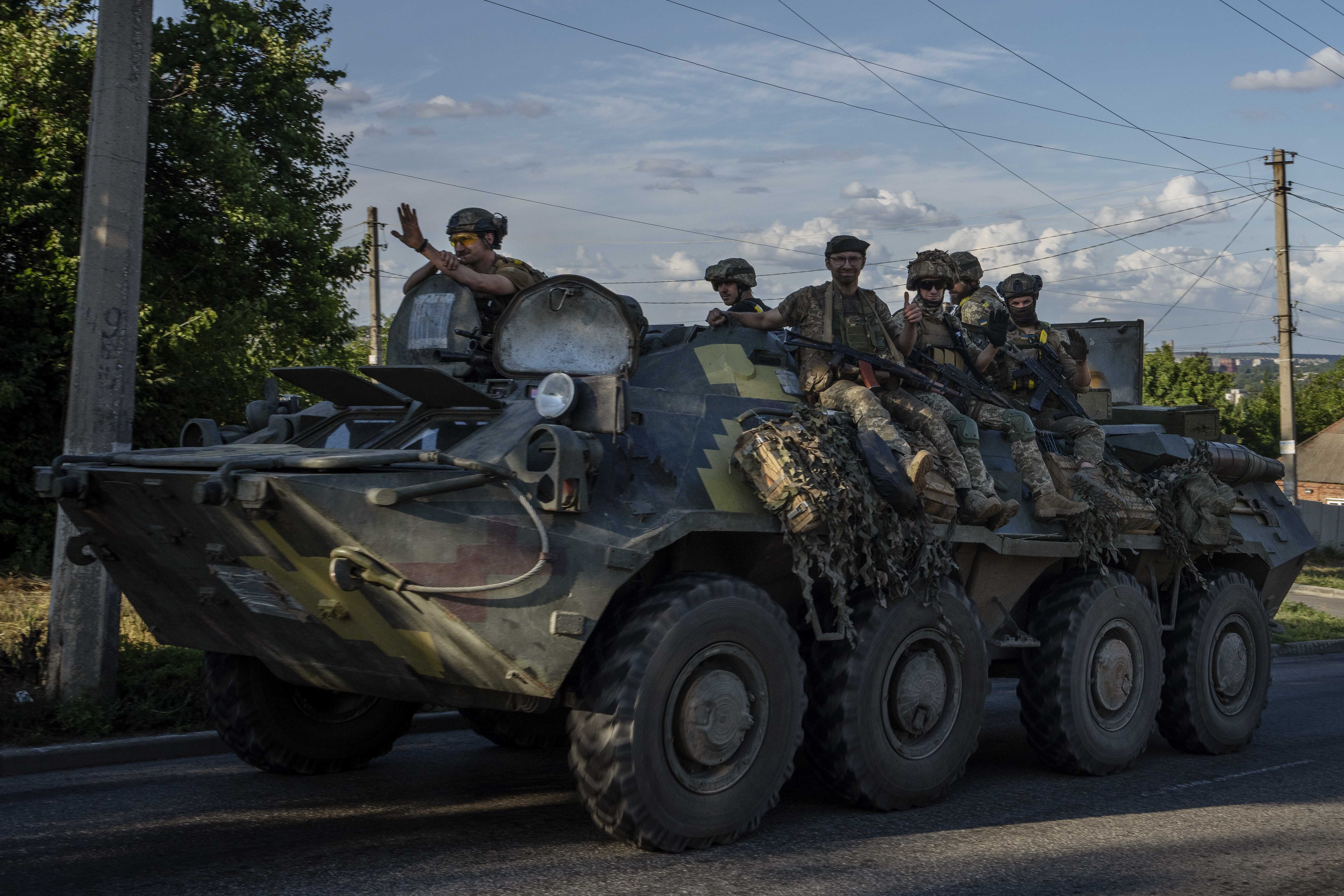 Ukrainian soldiers ride a tank, on a road in Donetsk region