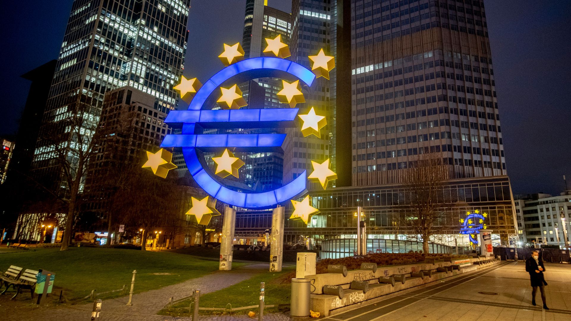 A man walks past the Euro sculpture in Frankfurt, Germany