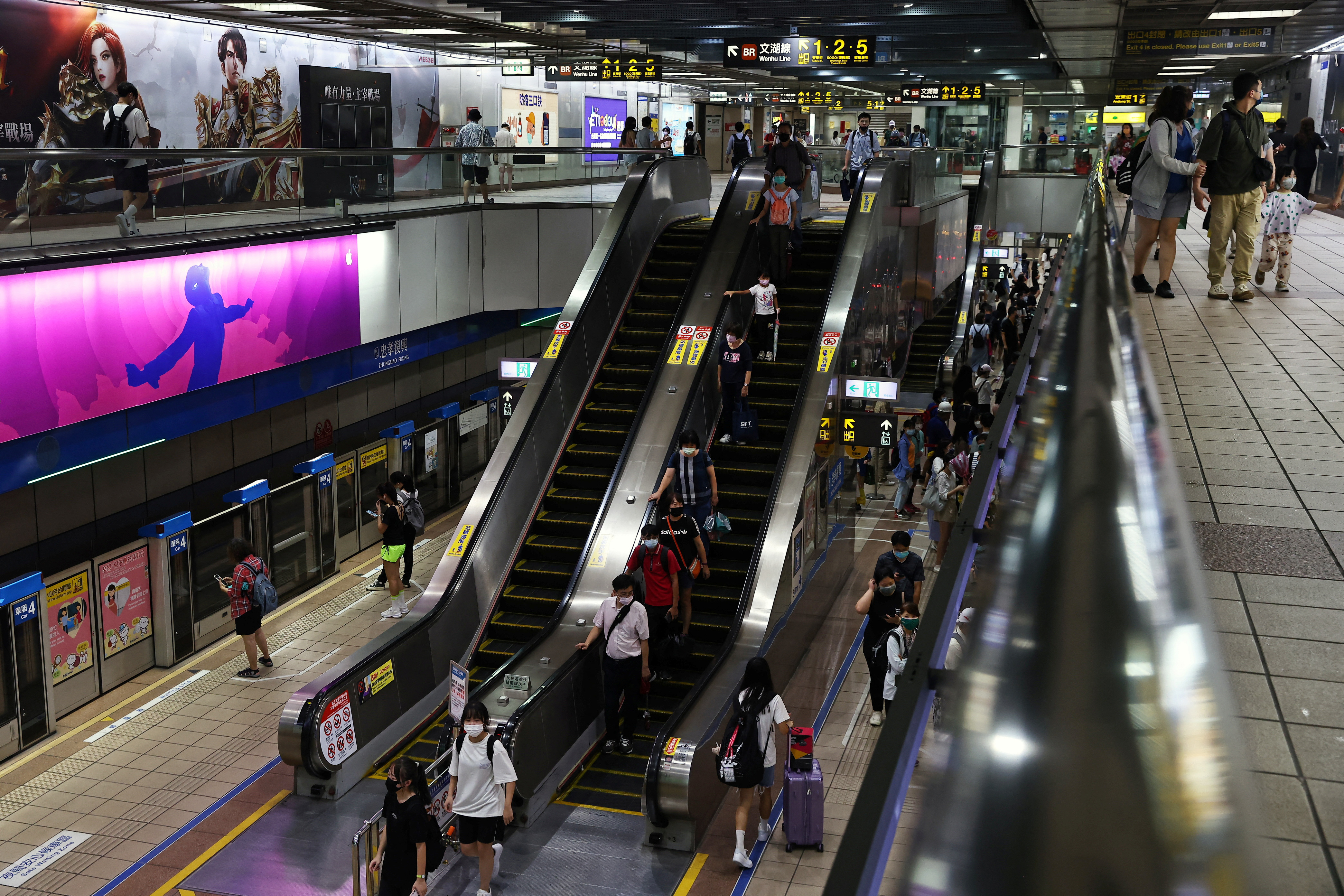 Commuters ride an escalator in an underground metro station, which will be used as an air-raid shelter