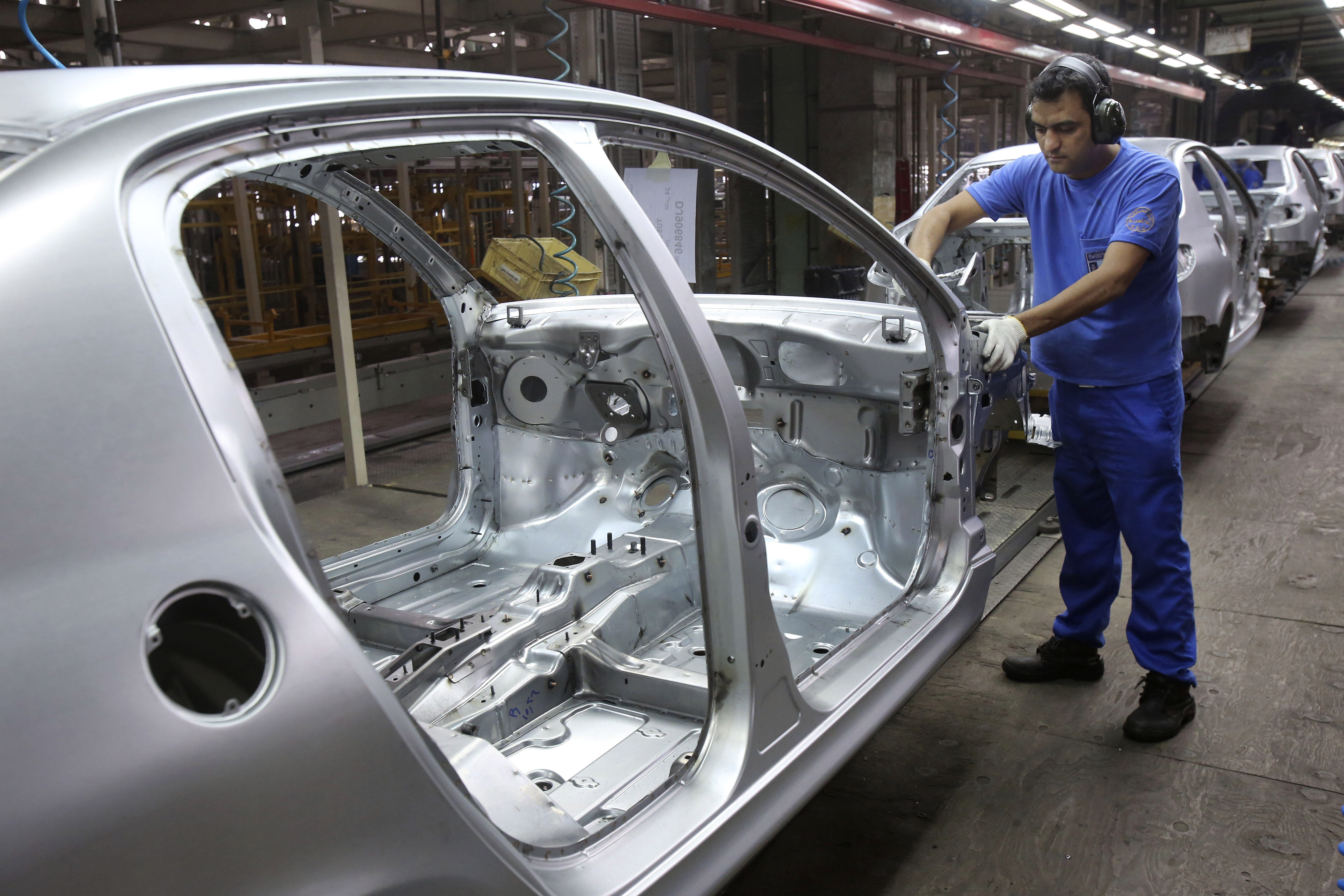 An Iranian worker pounds the body of a car at the Iran Khodro automobile manufacturing plant just outside Tehran, Iran