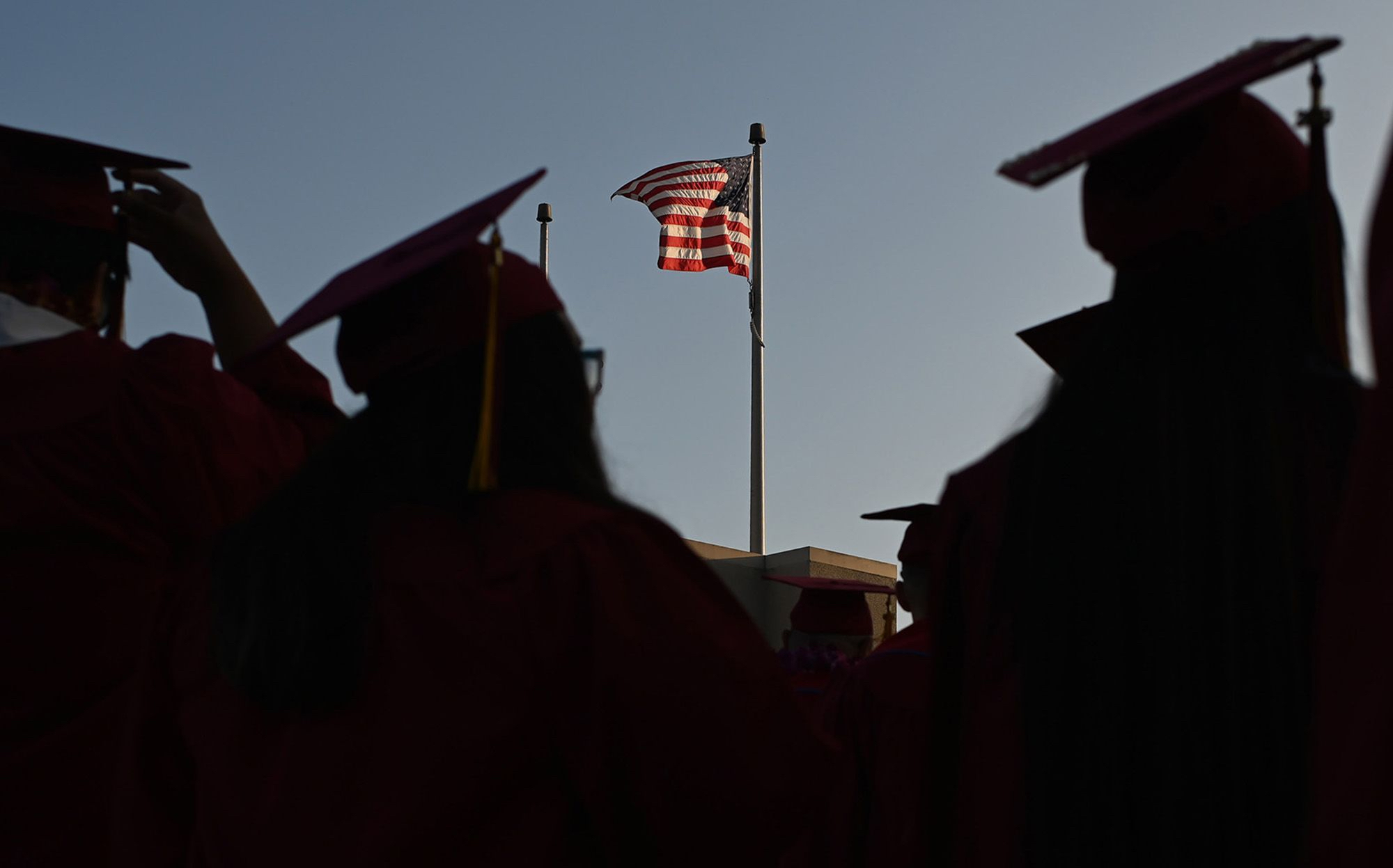 A US flag flies above a building as students earning degrees at Pasadena City College participate in the graduation ceremony