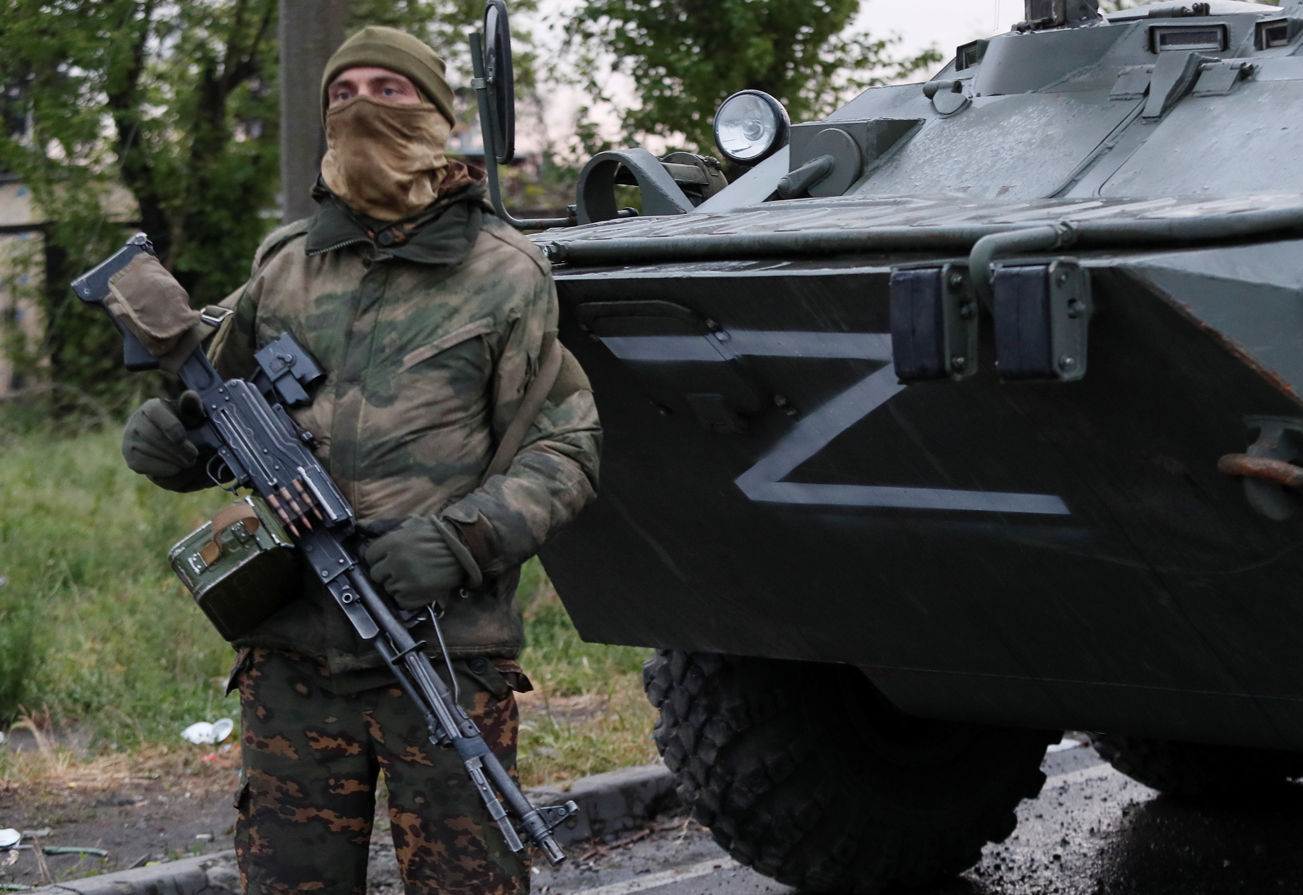 A Russian soldier stands guard in front of a tank with a Z on its front in Mariupol, Ukraine.