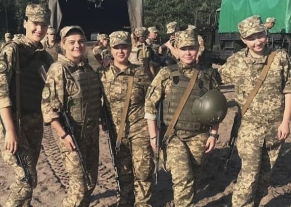 Anna and other women soldiers in uniform and bullet-proof vests next to each other.