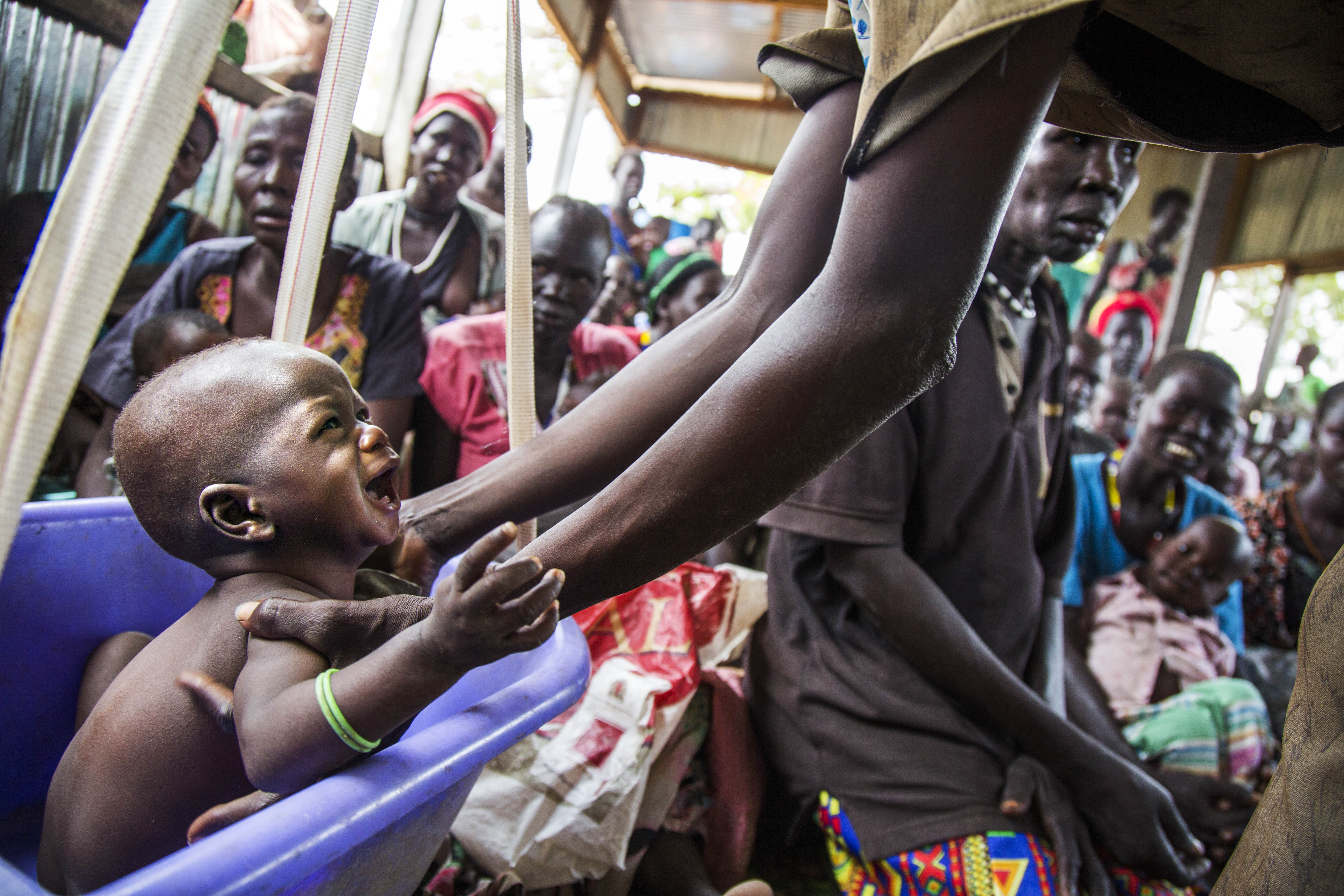 A mother weights her malnourished child on May 31, 2017, in a nutrition centre run by the International Rescue Committee (IRC) in Panthau, Northern Bahr al Ghazal, South Sudan. - An estimated 63 per cent of the population in Northern Bahr al Ghazal is experiencing severe food insecurity, according to the latest Integrated Food Security Phase Classification (IPC) report. The situation is particularly bad in Aweil West and Aweil South counties, where the exhaustion of household food stocks and growing dependence on financially inaccessible markets have left the population facing Emergency levels of food insecurity.