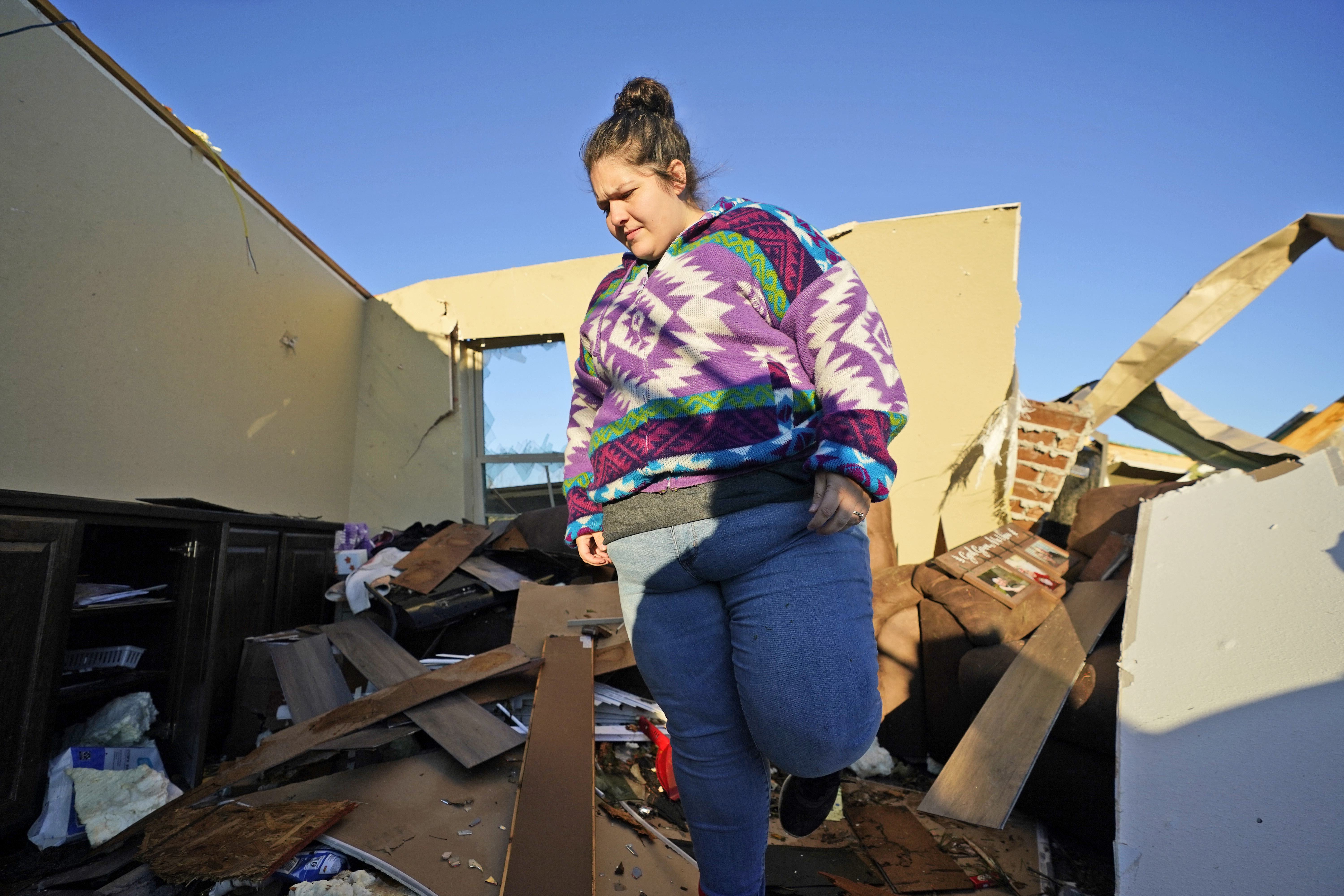 Sydnie Dooley walks through the ruined remains of what was once her living room while looking for items to salvage after a tornado hit Powderly, Texas.