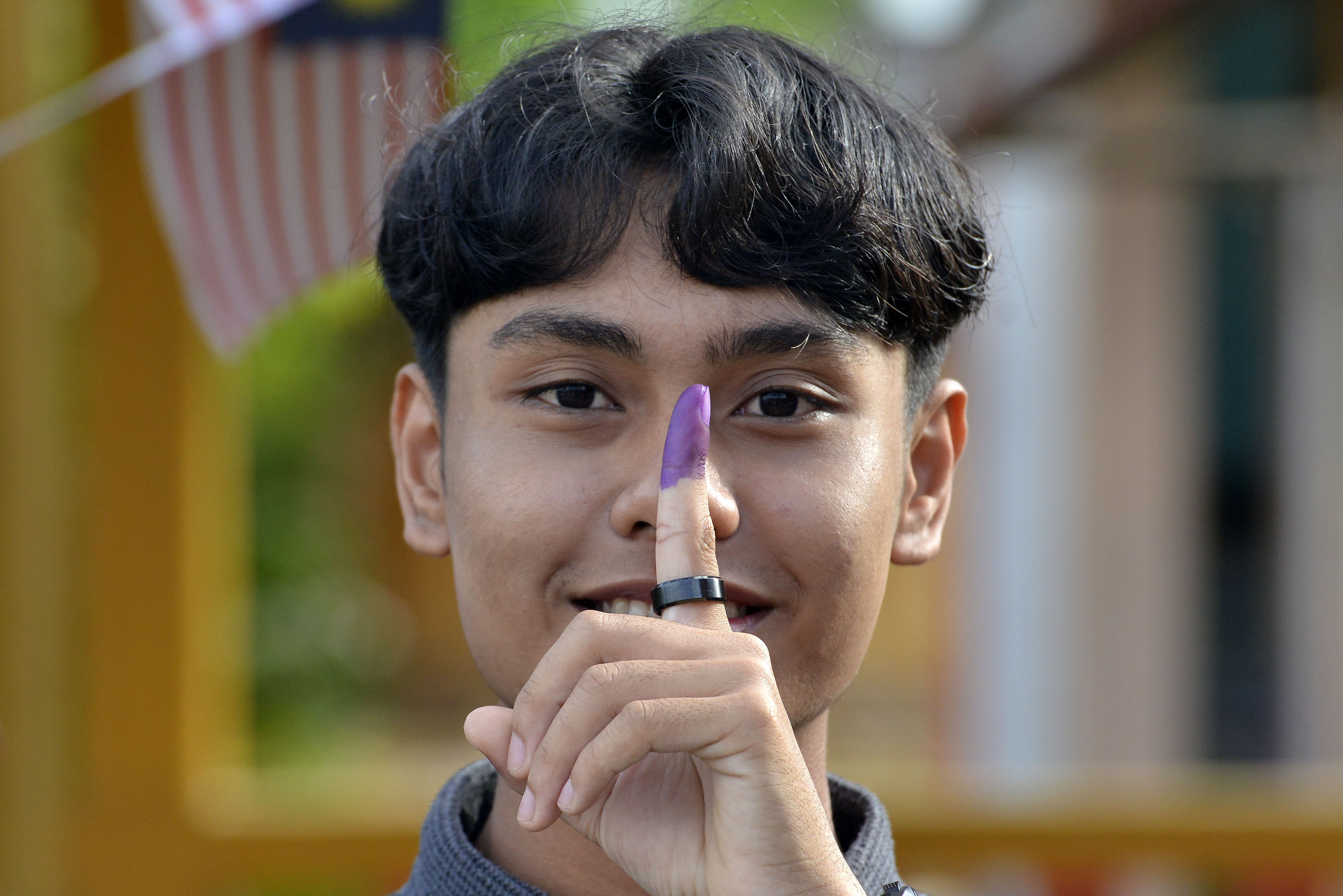 A young male voter shows his inked finger after casting his ballot in Malaysia