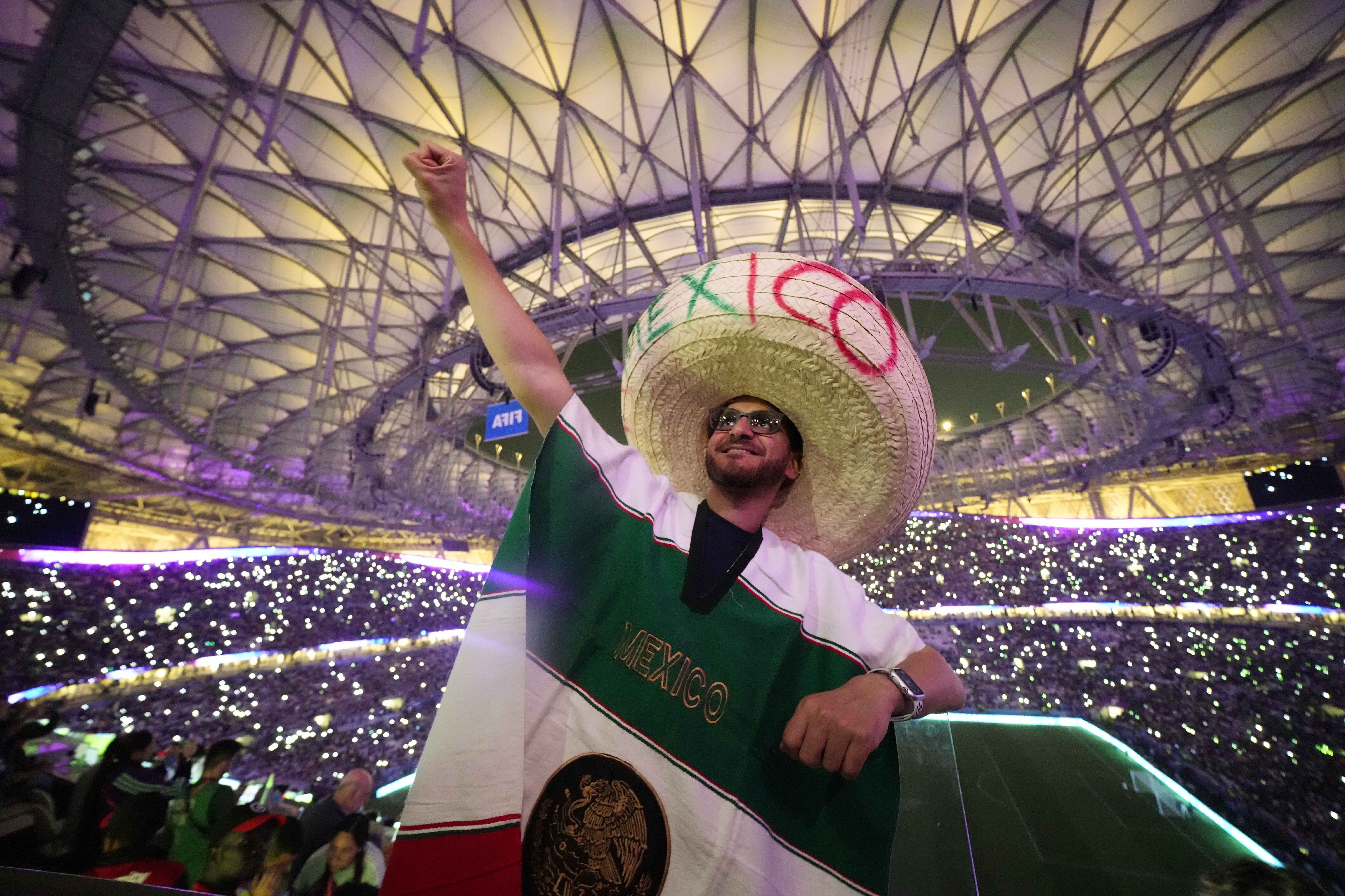 Karima Mohammed of Egypt cheers on Mexico with a raised fist as wears a sombrero with the letters Mexico written on it and a Mexican flag drapes his body.