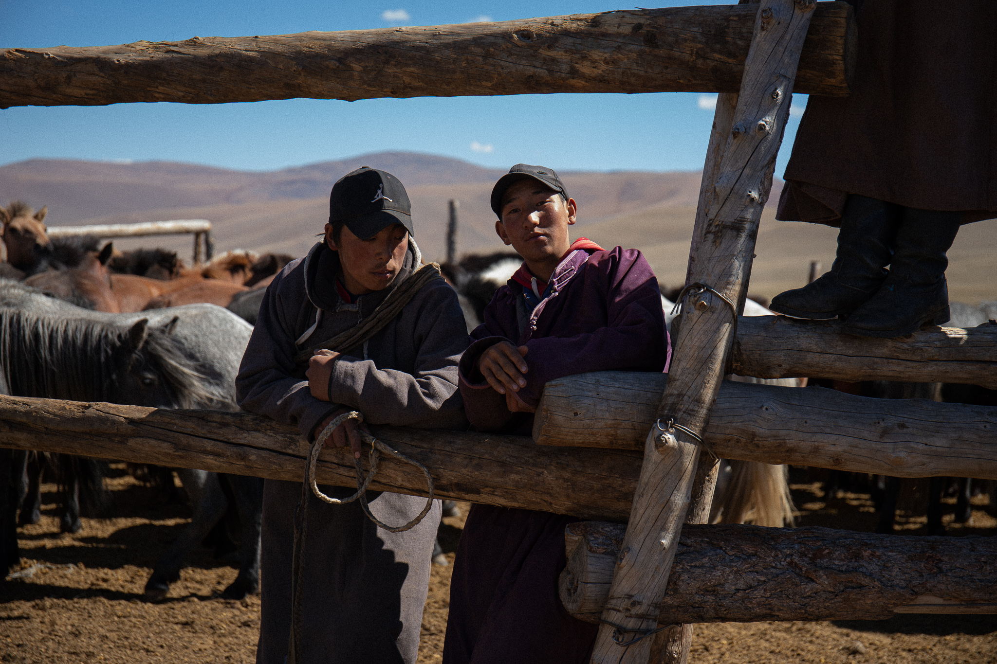 Bakhtur, 22 (Left) and Shwara, 18, (right) leaning against a fence where horses are corralled. They look happy