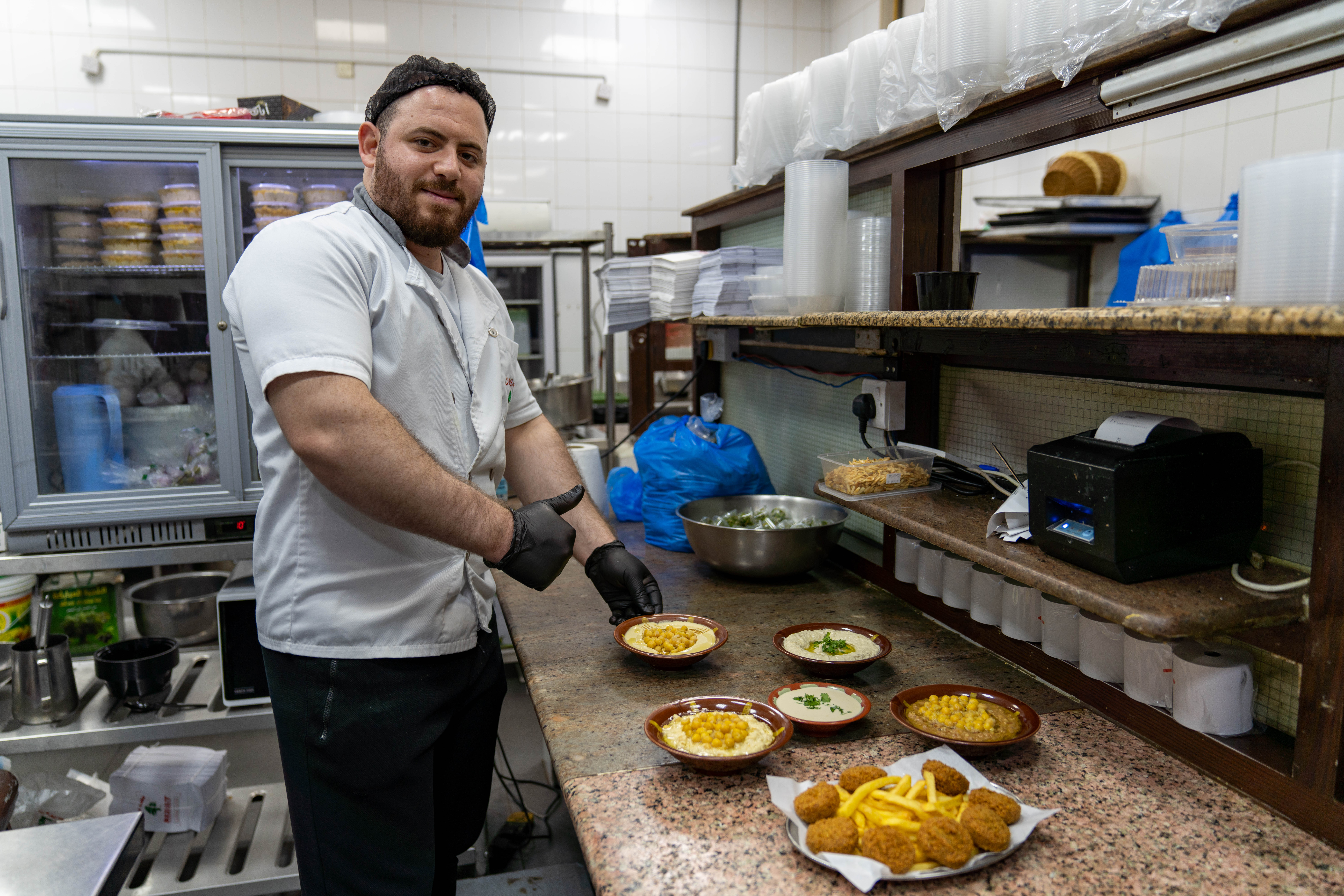 Chef Mohamed flashing a thumbs-up as he prepares a number of dishes to go out to the dining room